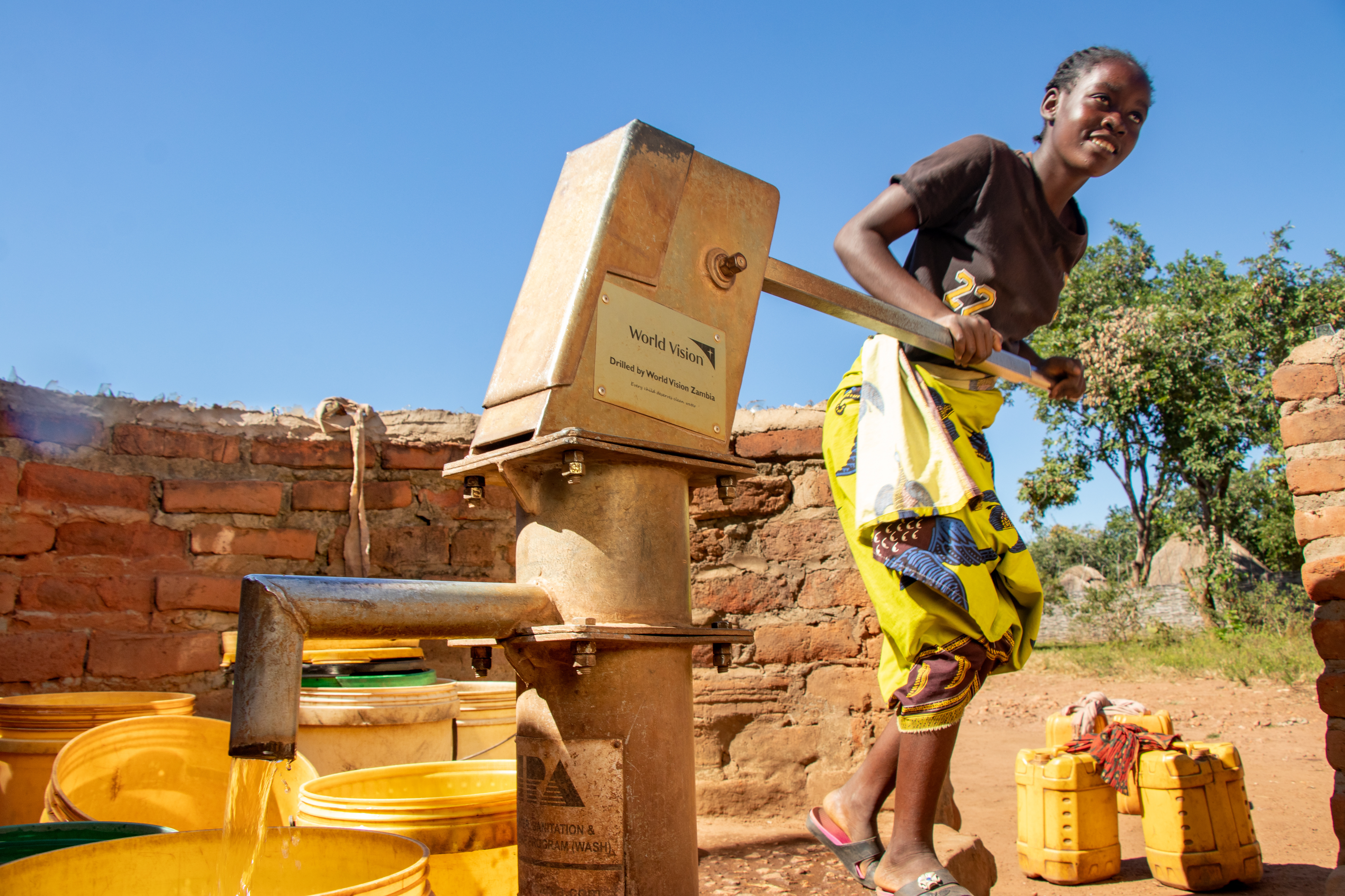 A girl in Zambia uses a borehole pump to collect clean water for her family