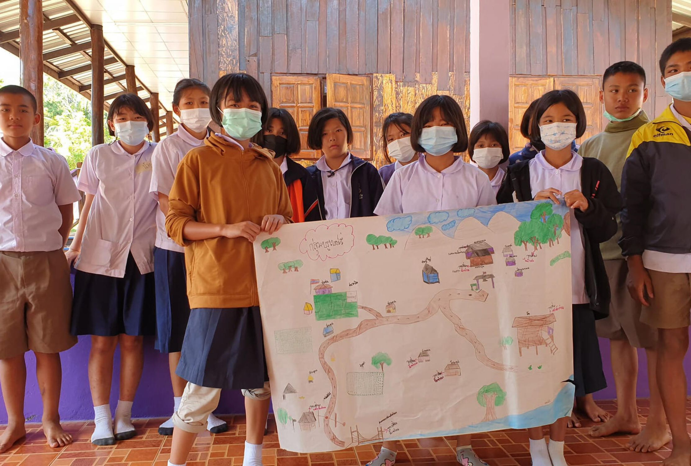 Thai school children holding a hand-drawn map of flood risk areas and safe spots in their village.