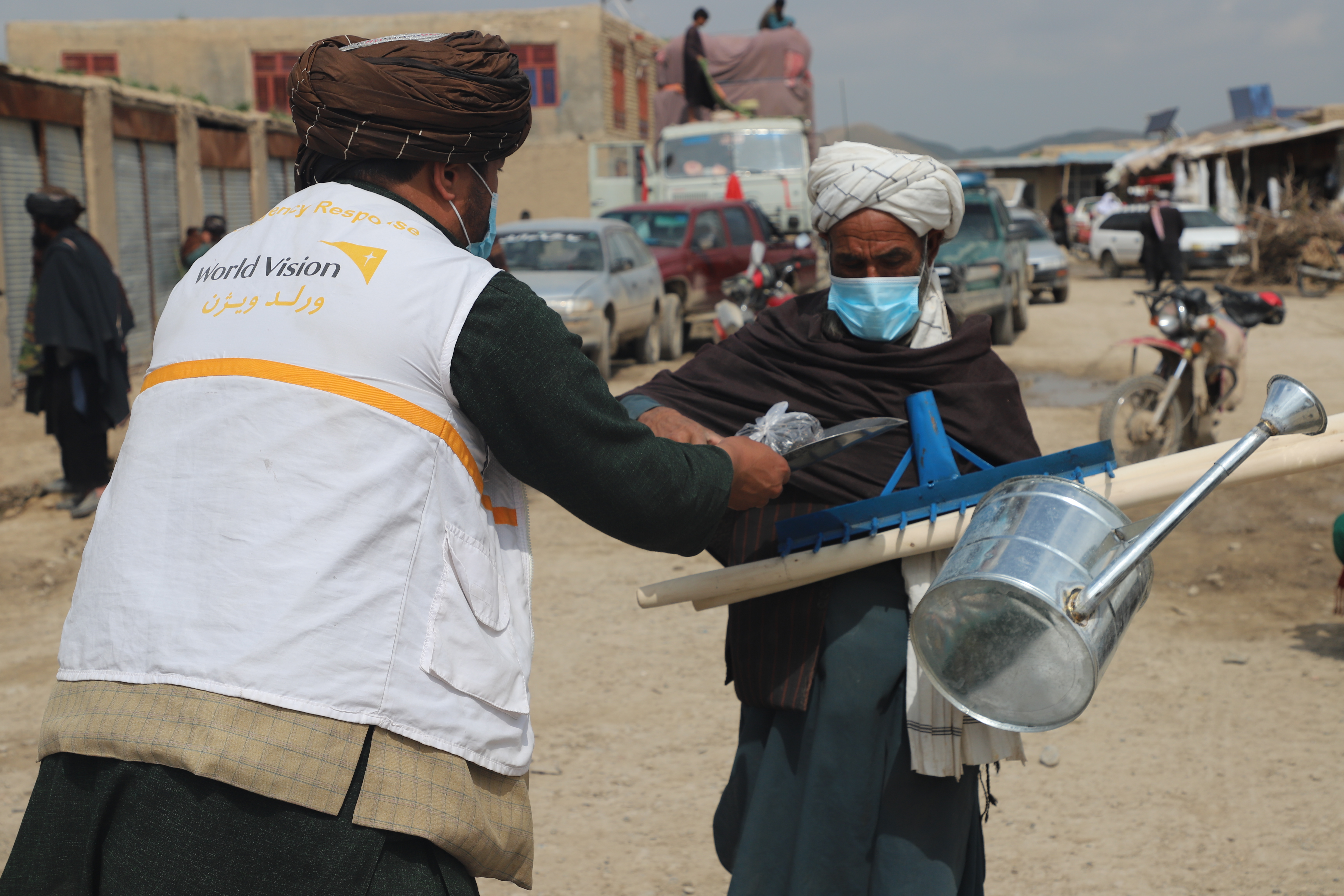 Agricultural worker in Afghanistan receiving a farming toolkit from a World Vision volunteer
