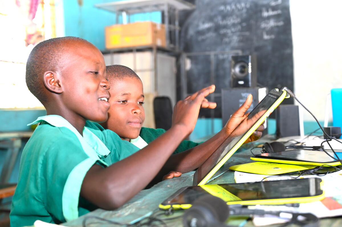 Two Kenyan children wearing school uniform and taking part in new e-learning activities on a tablet