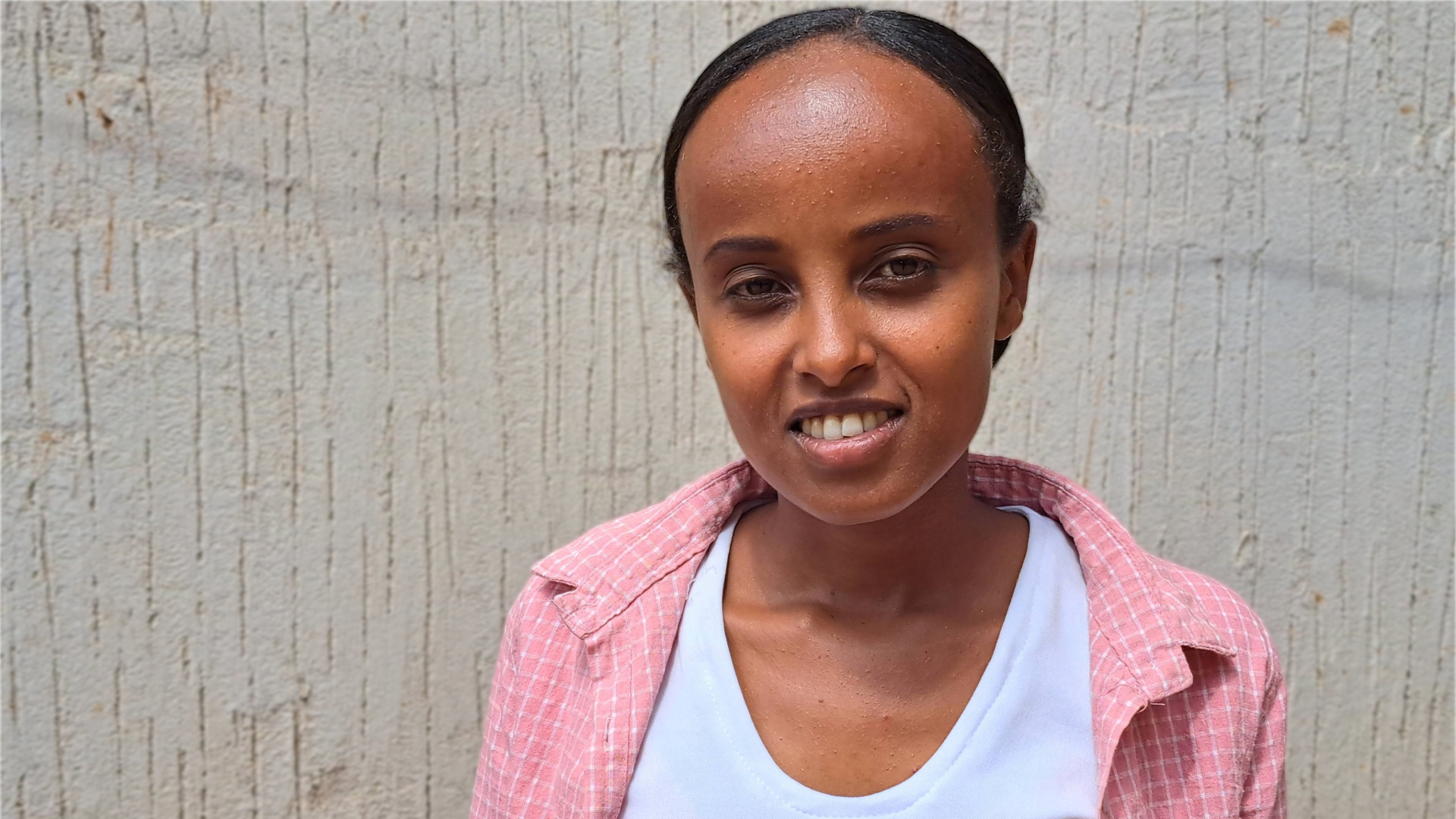 Former sponsored child smiles outside her home in Ethiopia.