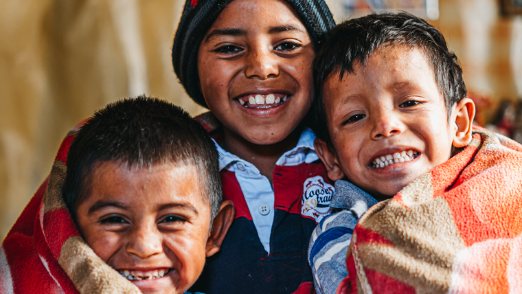 Victor and his two little brothers wrap up in the new blanket