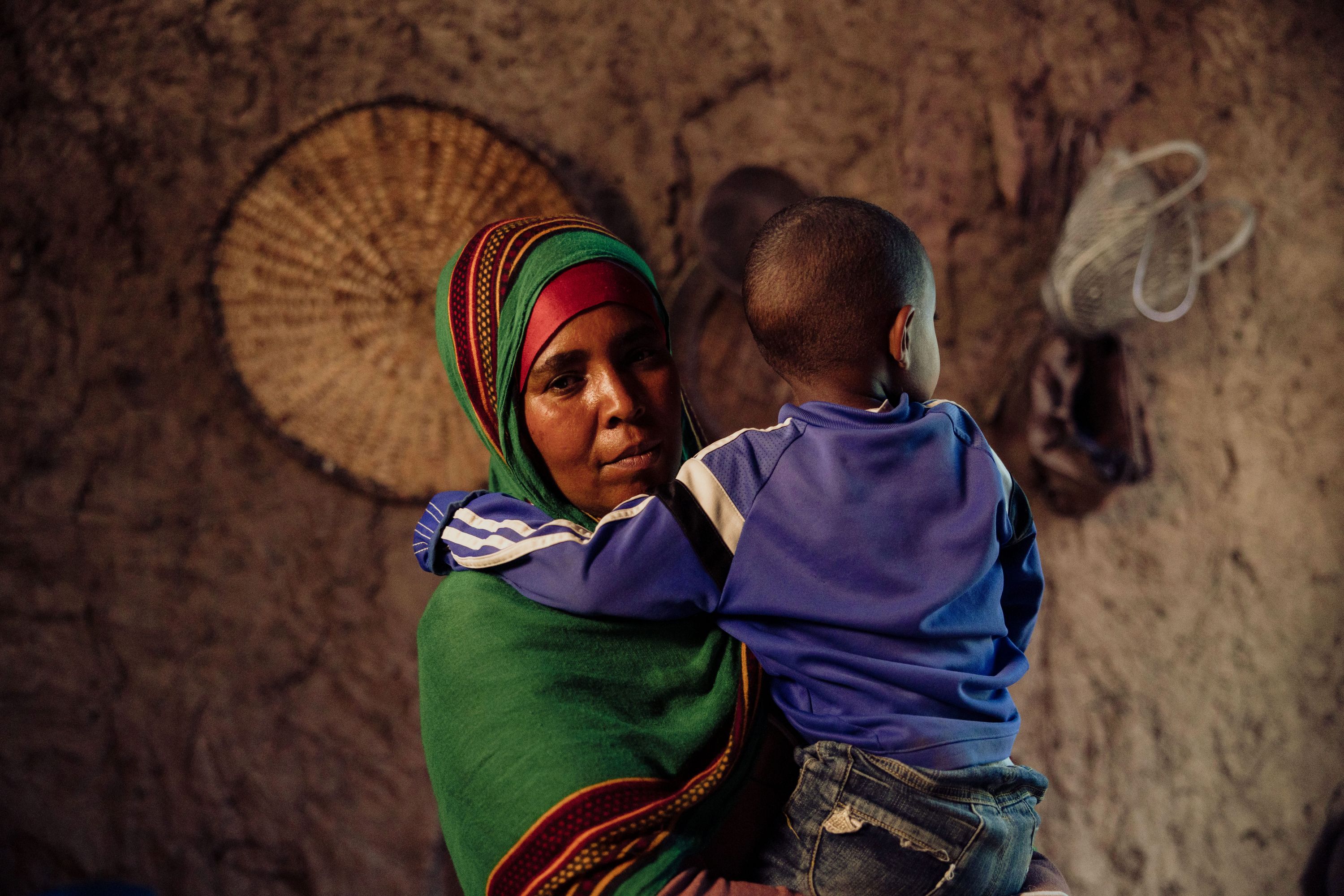 Mother Hindiya, in bright green headscarf, holds three-year-old Nuredin who is now a healthy weight
