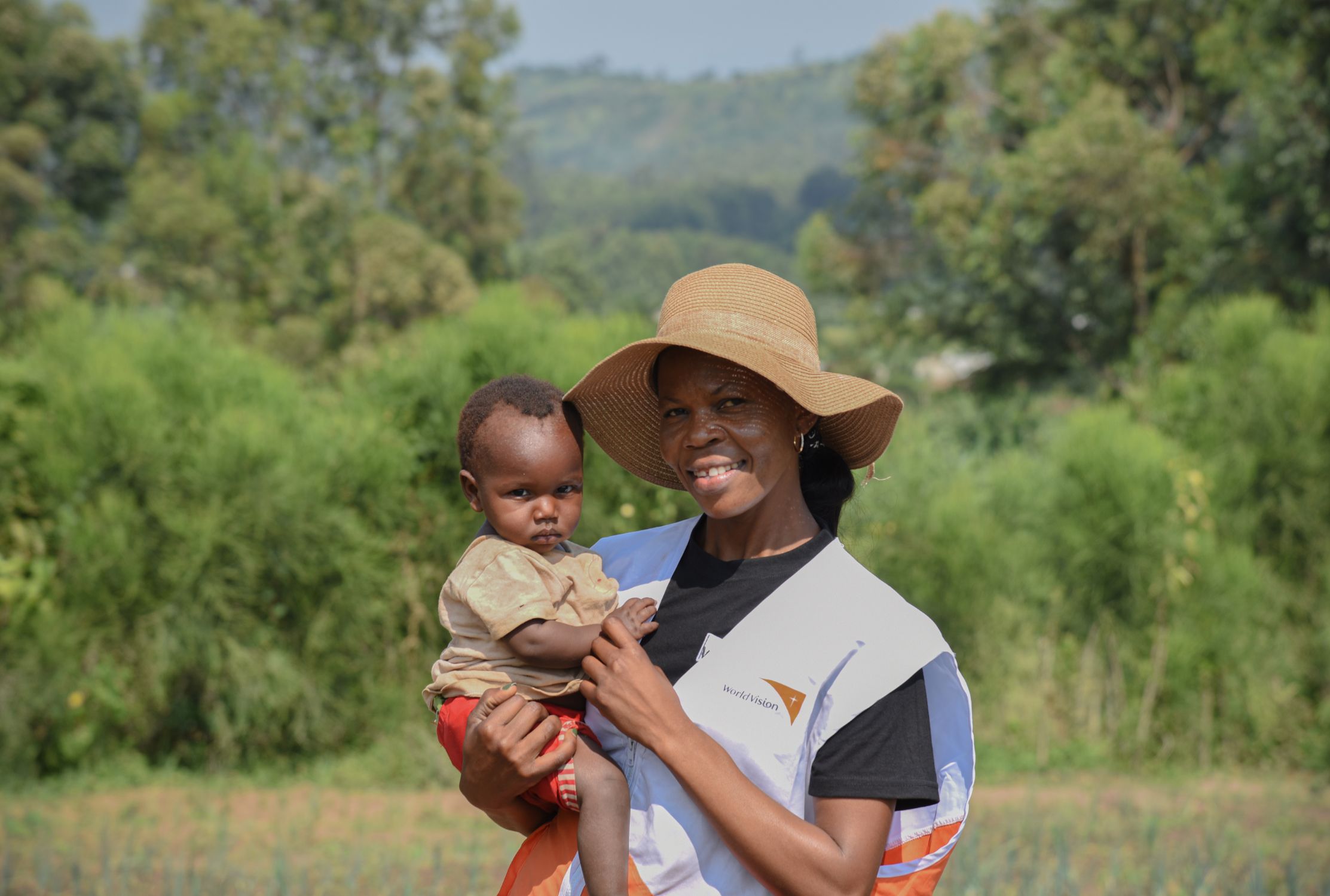 World Vision staff member holding one-year-old girl from DRC