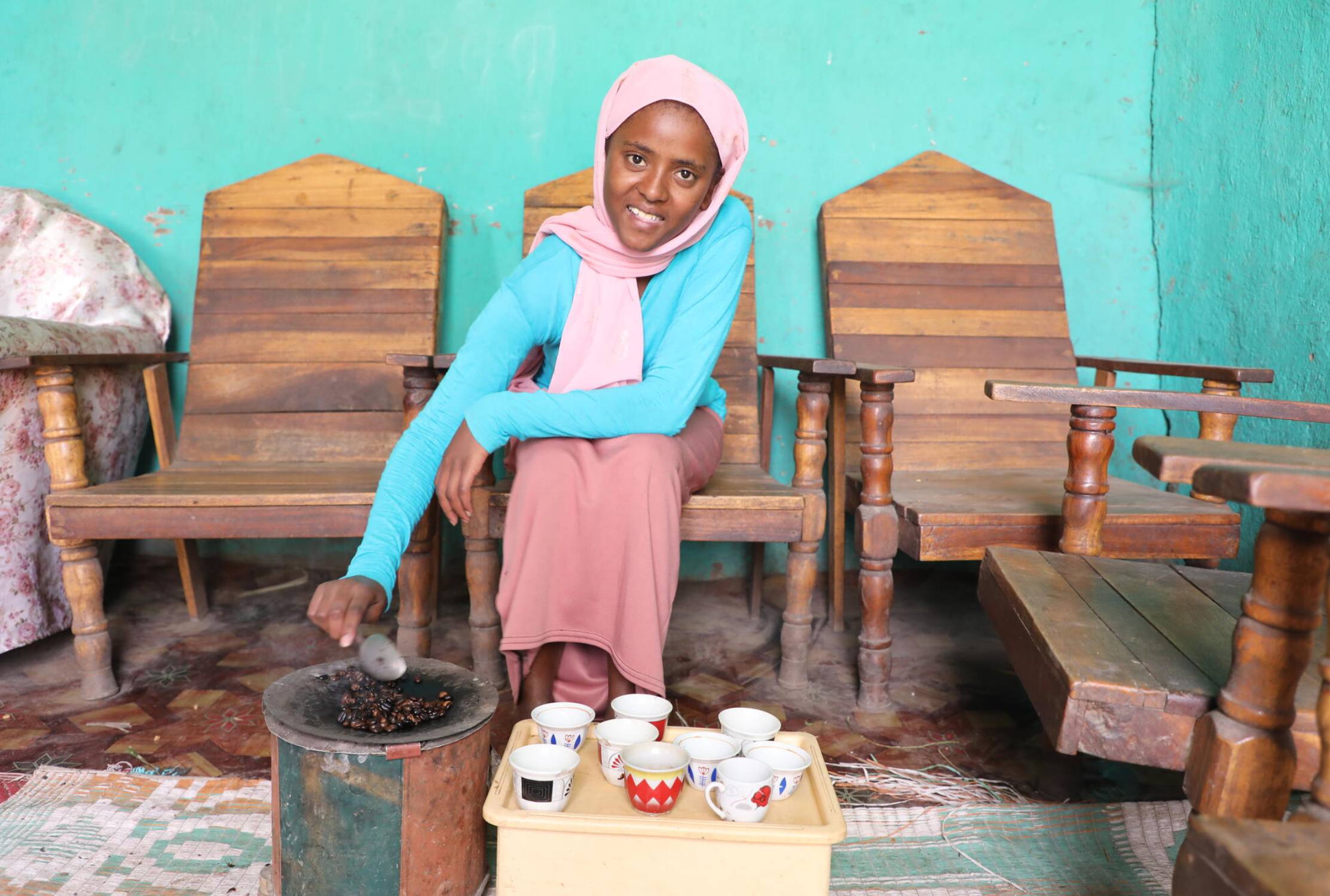 Girl from Ethiopia roasting coffee beans while smiling