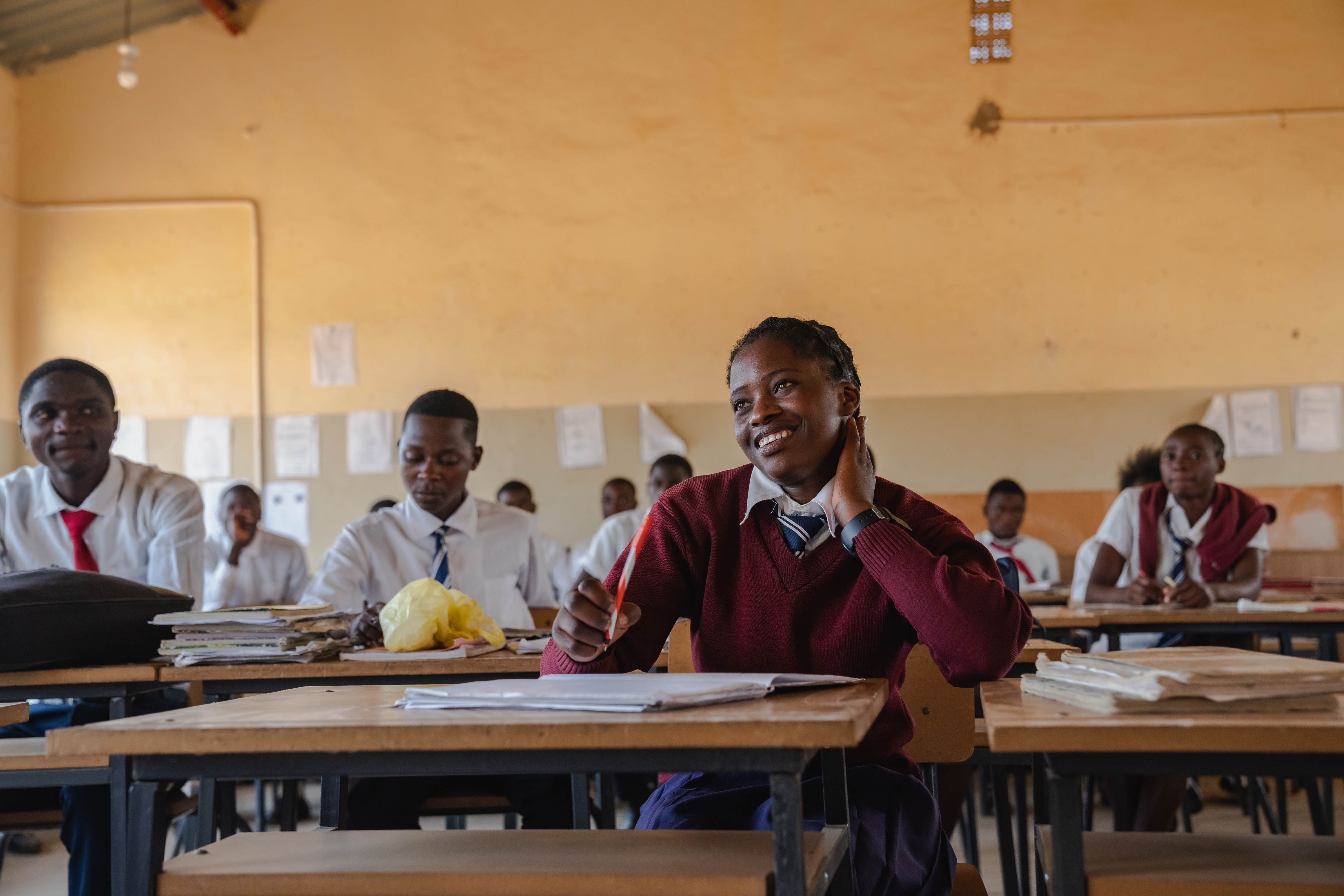 A child in Zambia sits at a school desk amongst peers