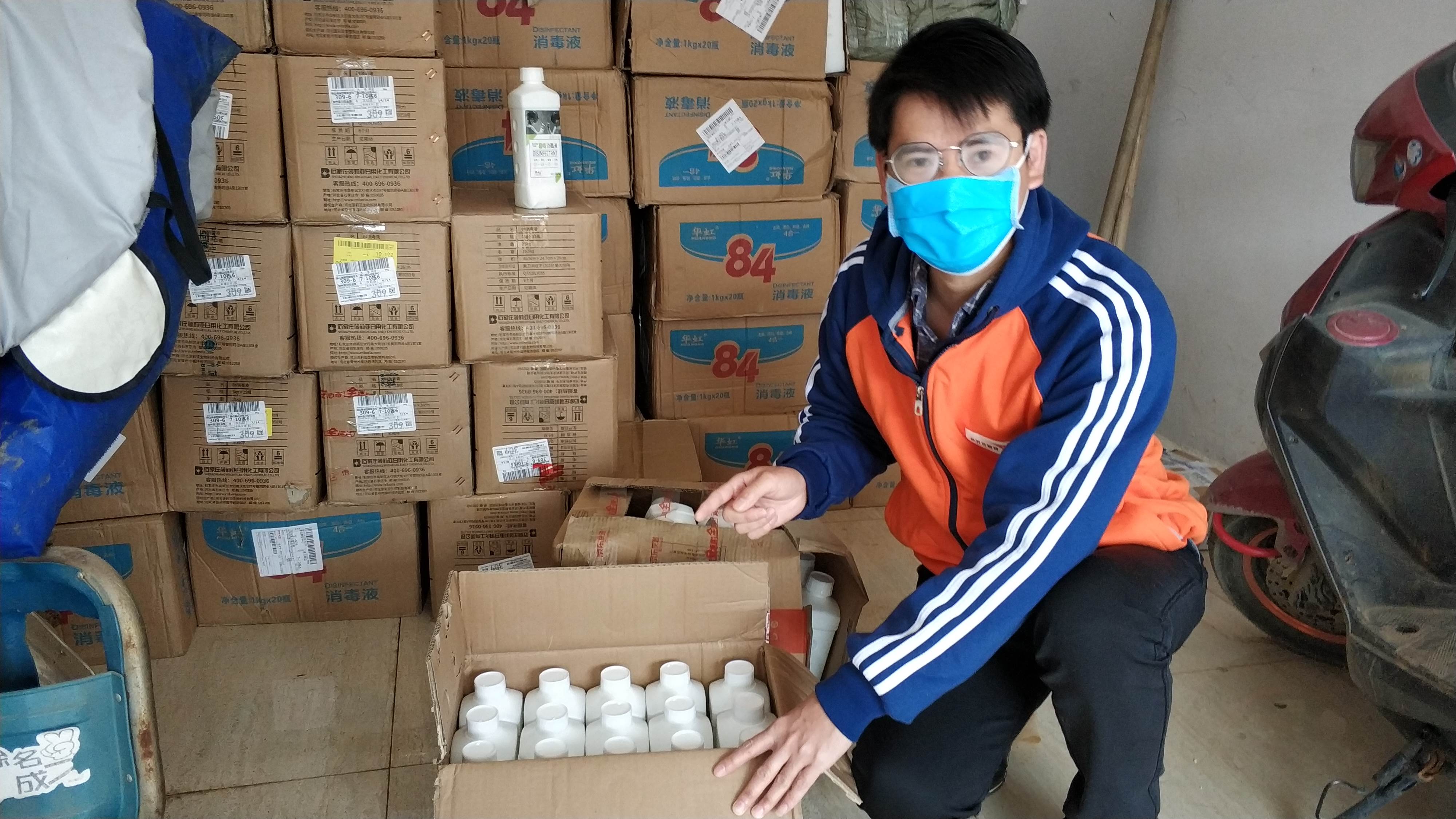 Man in China wears a mask as he sits next to boxes of supplies