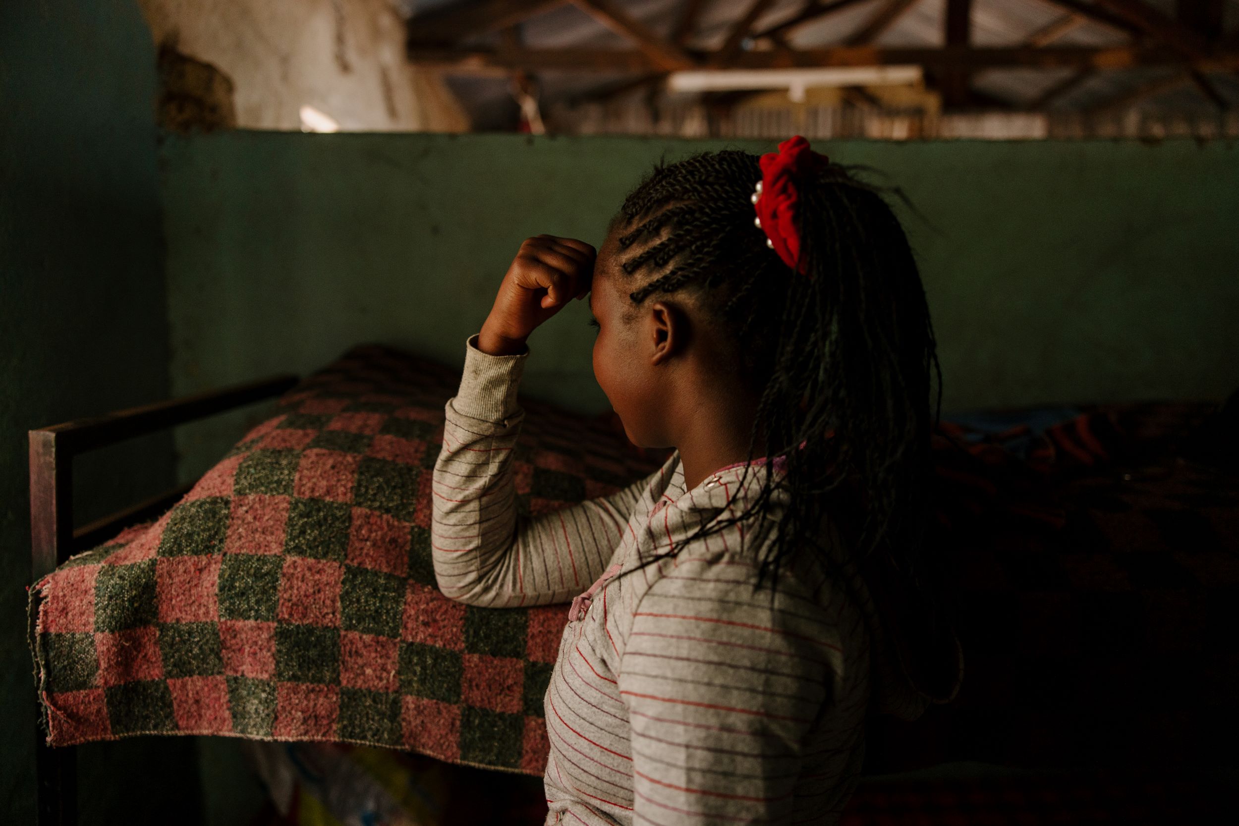 Kenyan girl with ponytail and stripy top. Face hidden, turned to the side to protect identity.