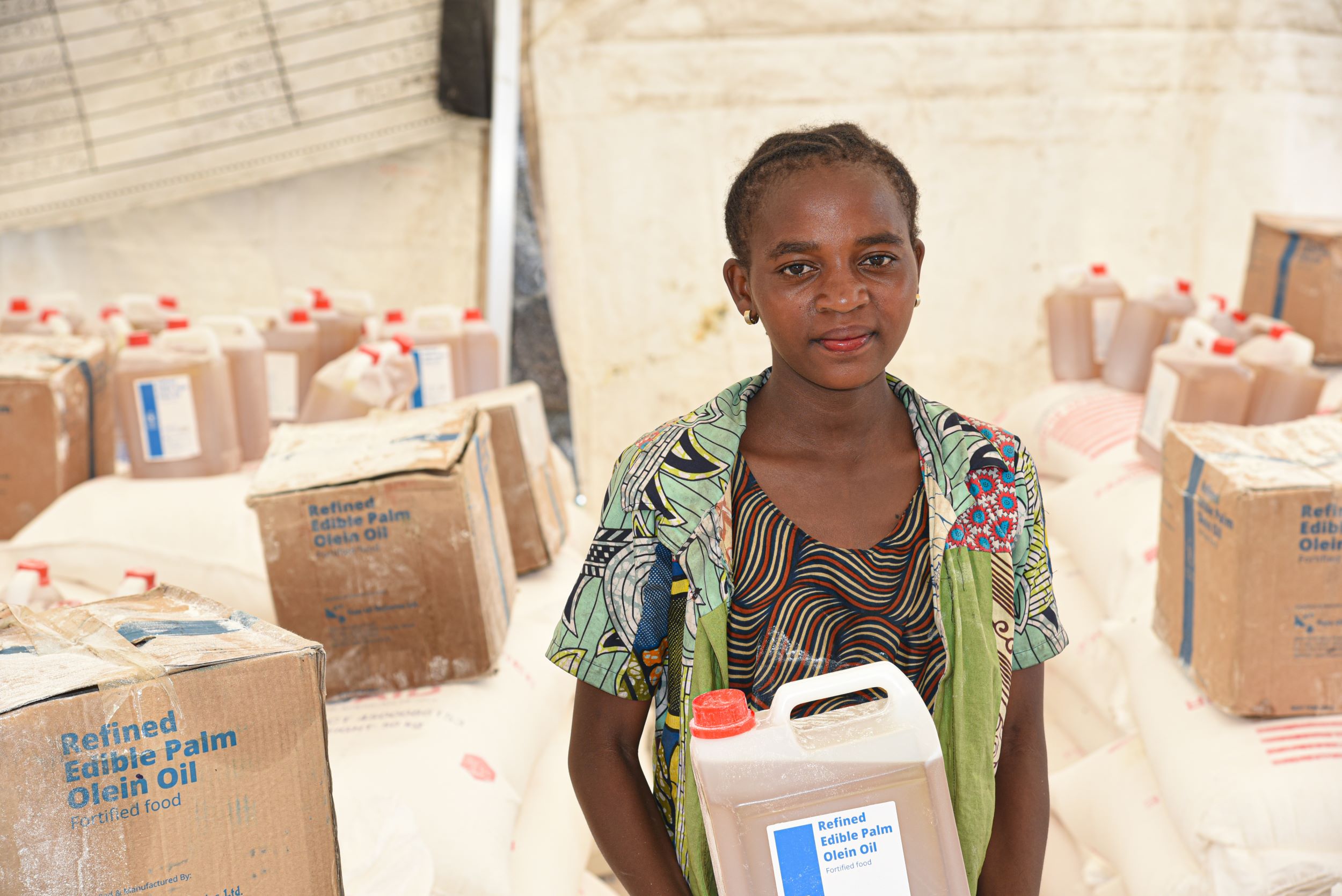 A young girl in DRC holding a container of oil received through World Vision 