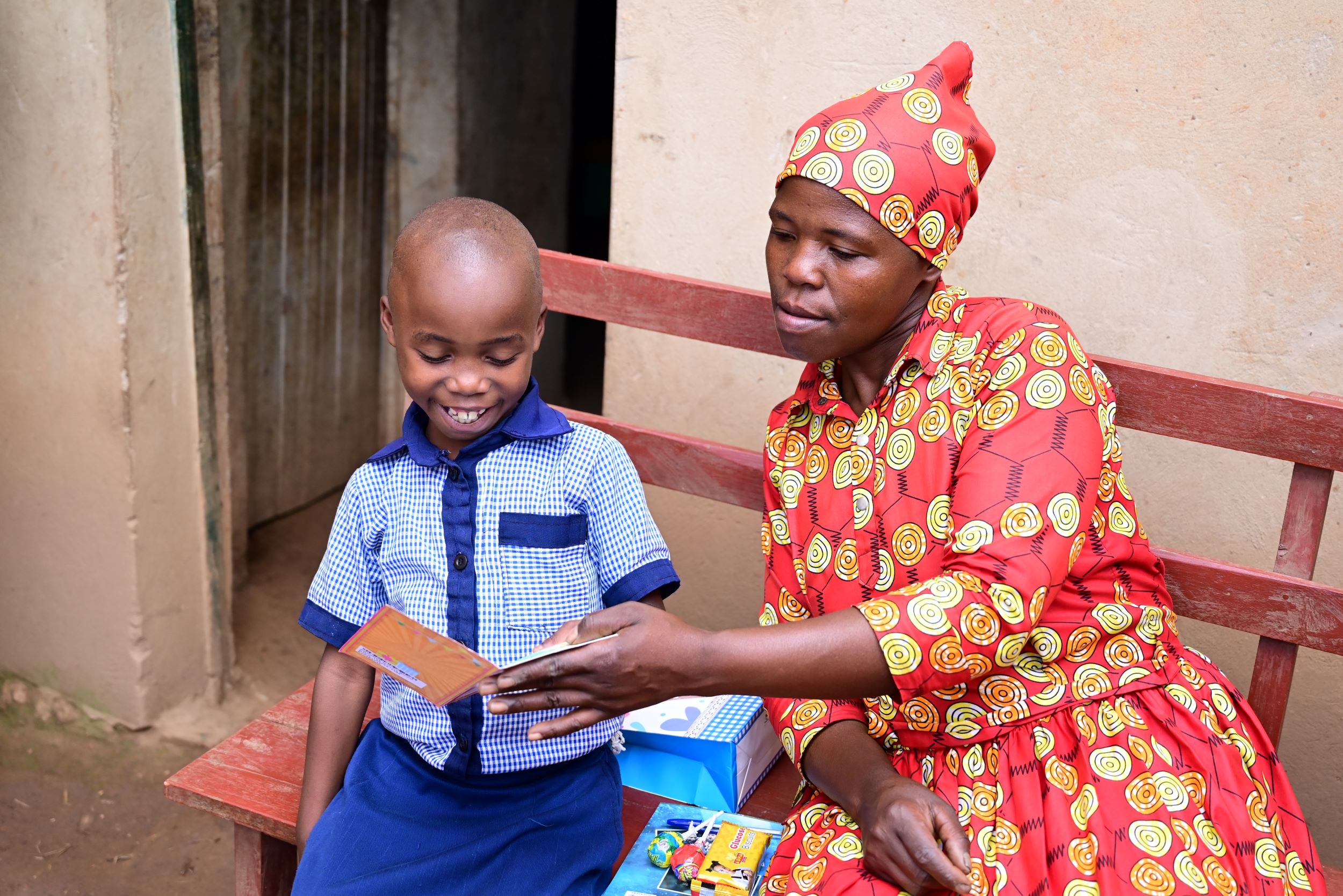 Rwandan child reading a card with mother