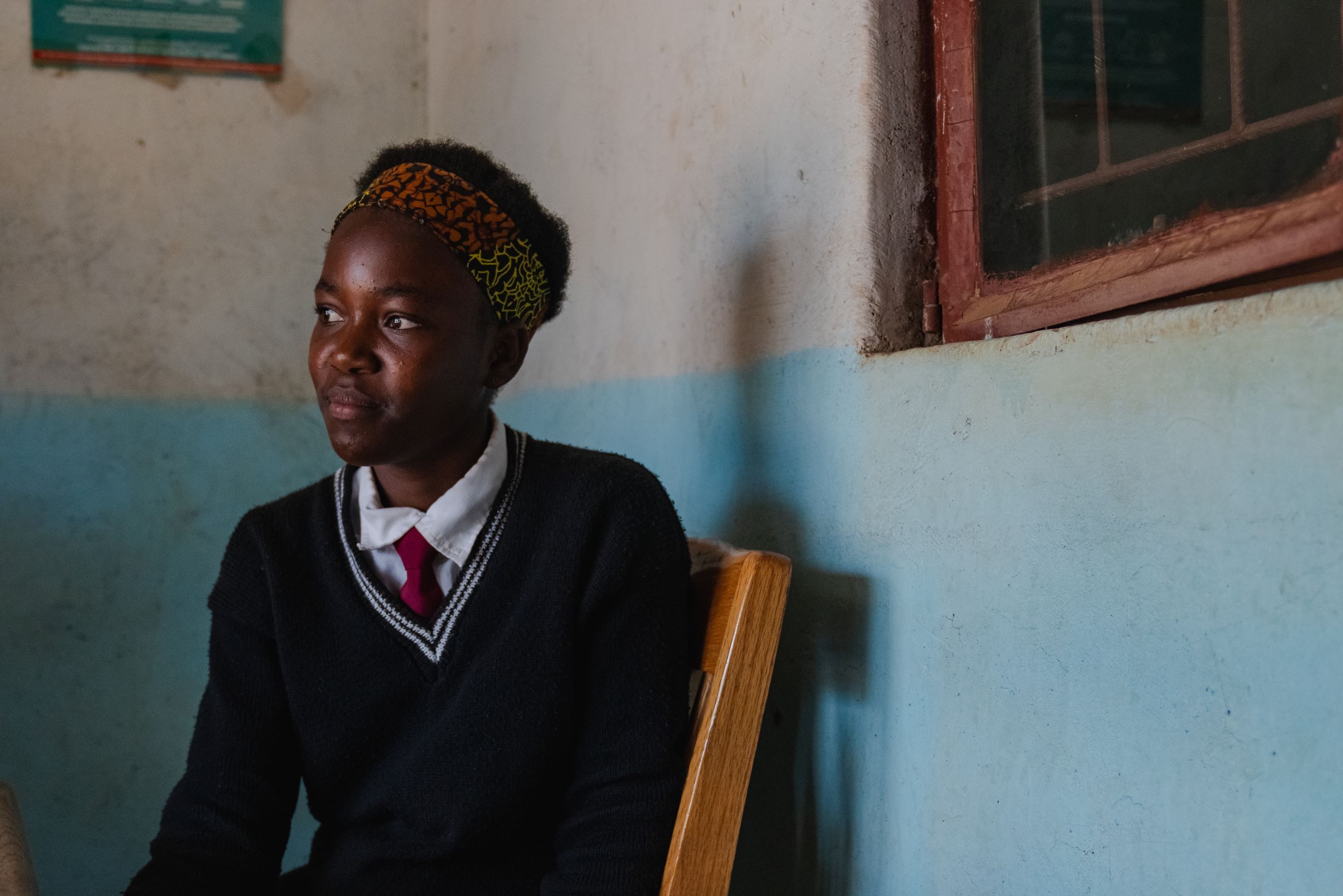 Zambian girl smiling as she sits wearing her school uniform