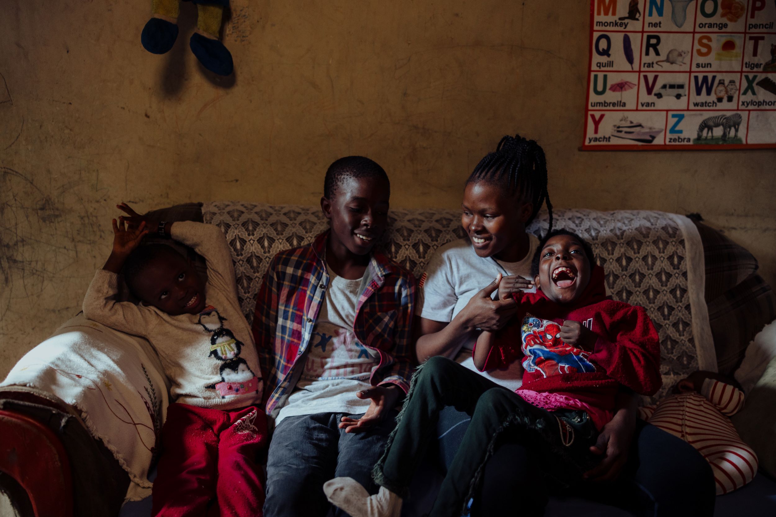 Members of a family in urban Kenya, sitting on their sofa and smiling