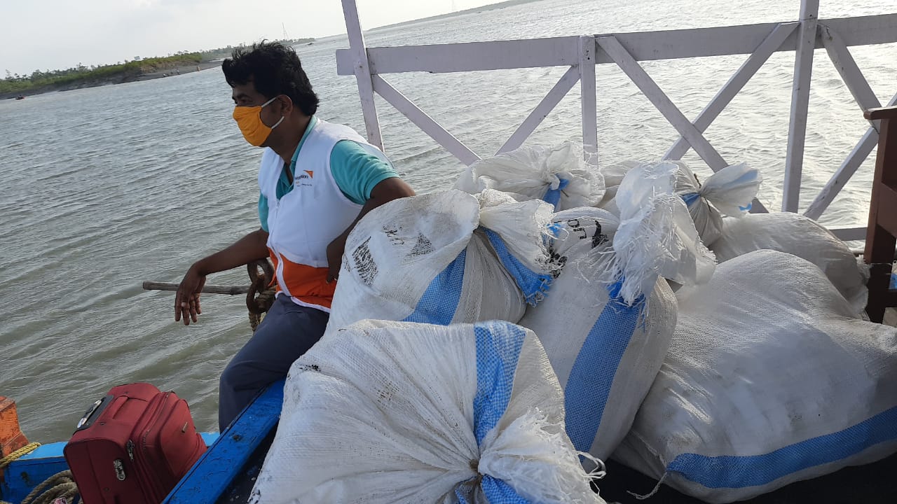 A World Vision worker sits on the side of a boat in India, delivering supplies to vulnerable families during COVID-19