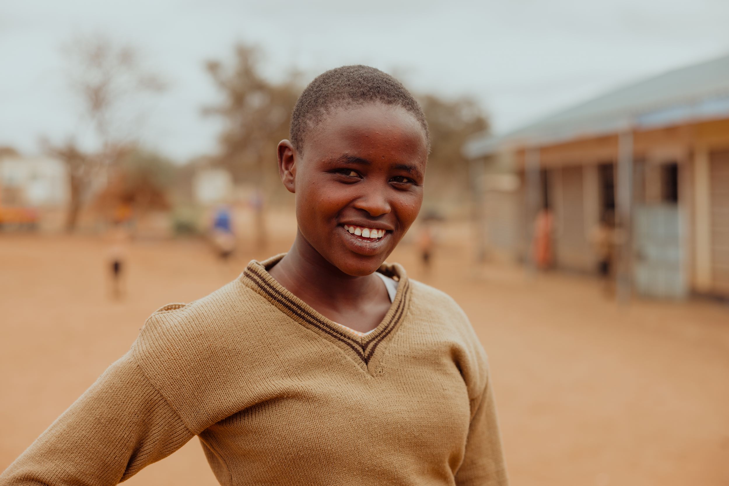Smiling Kenyan school girl in beige jumper