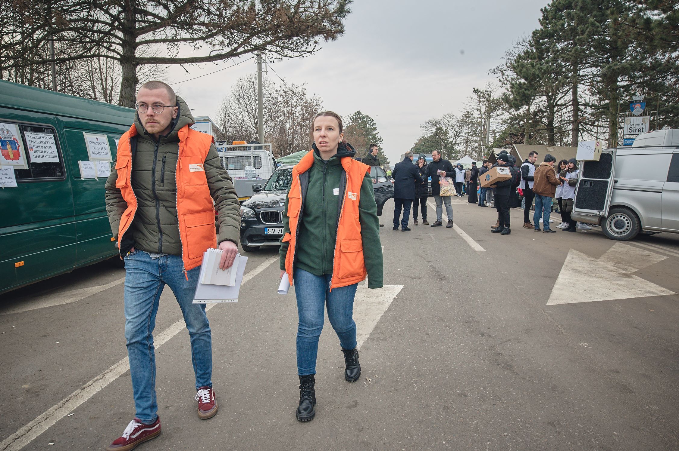World Vision staff members carry documents and walk through a crowded area where supplies are being distributed