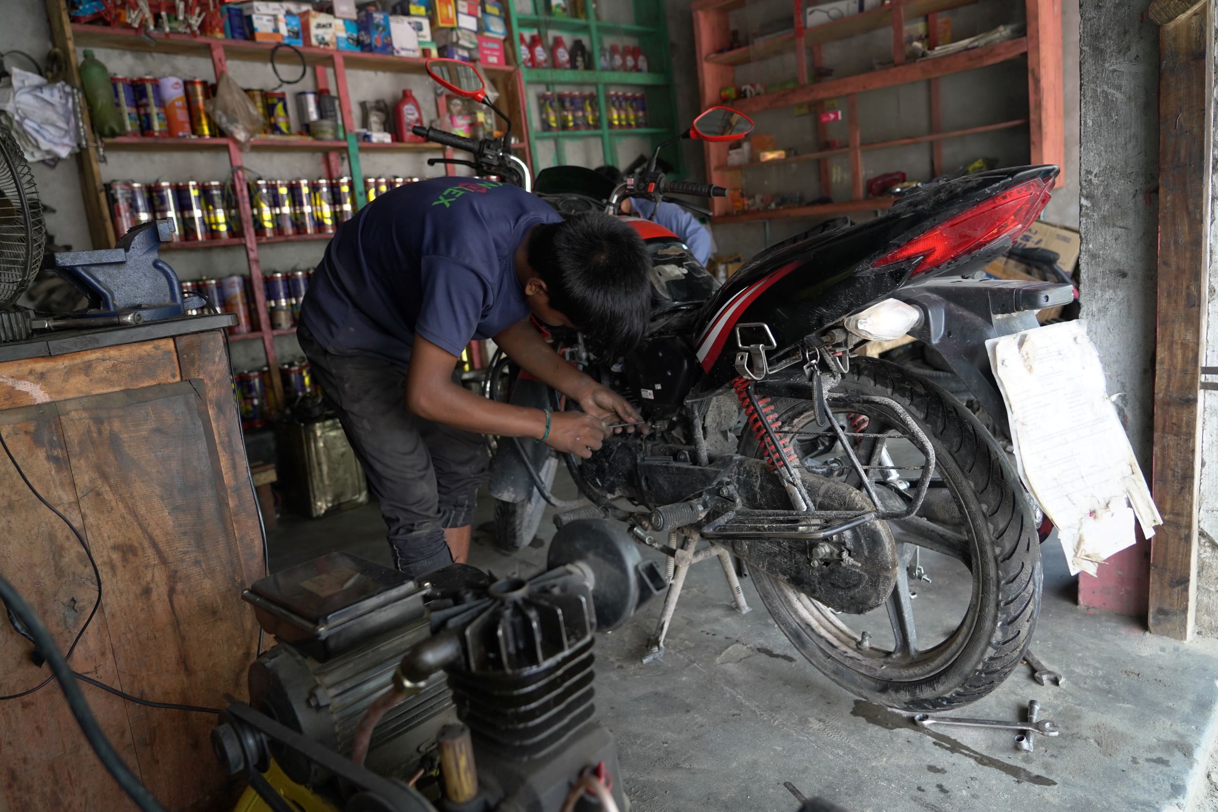 Boy from Bangladesh working on a motorcycle repair