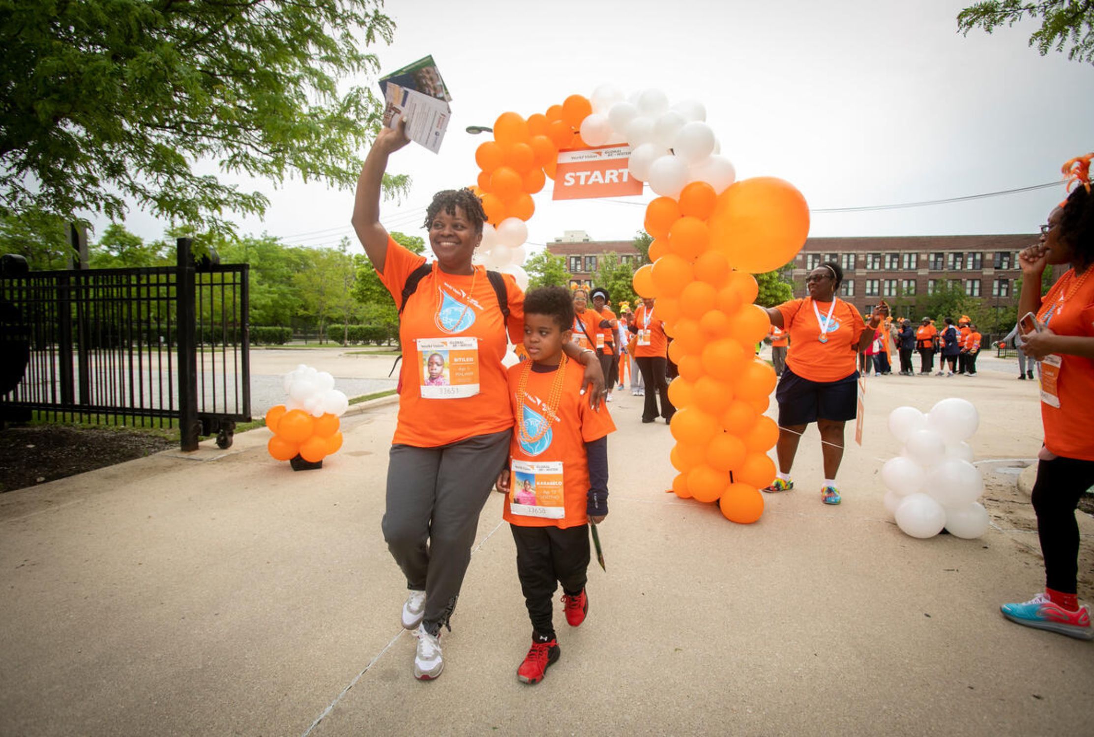 Mum and son walking an orange balloon arch to celebrate completing the Global 6K walk