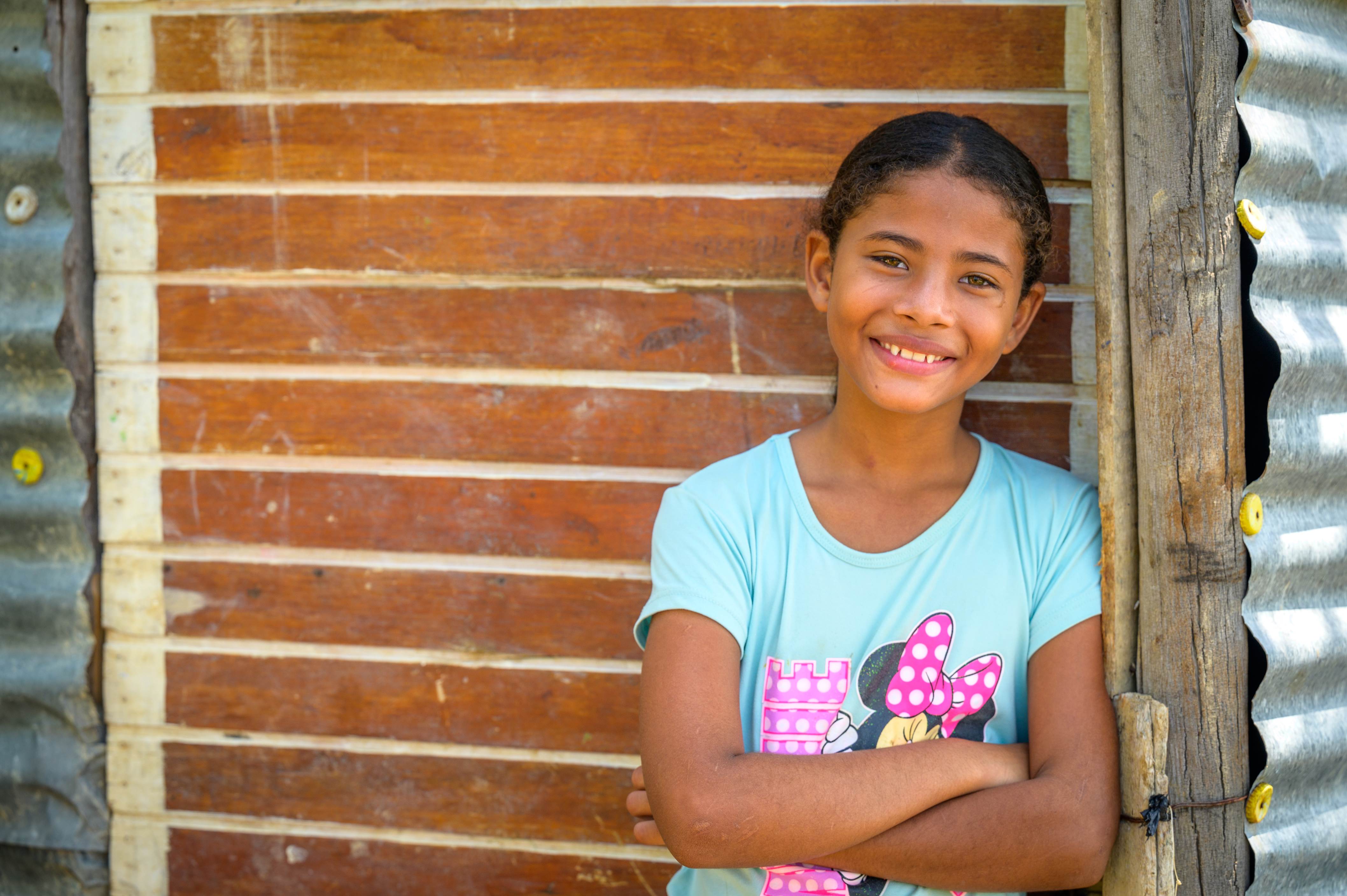 Sofia leans against a wall, arms crossed, smiling to camera.