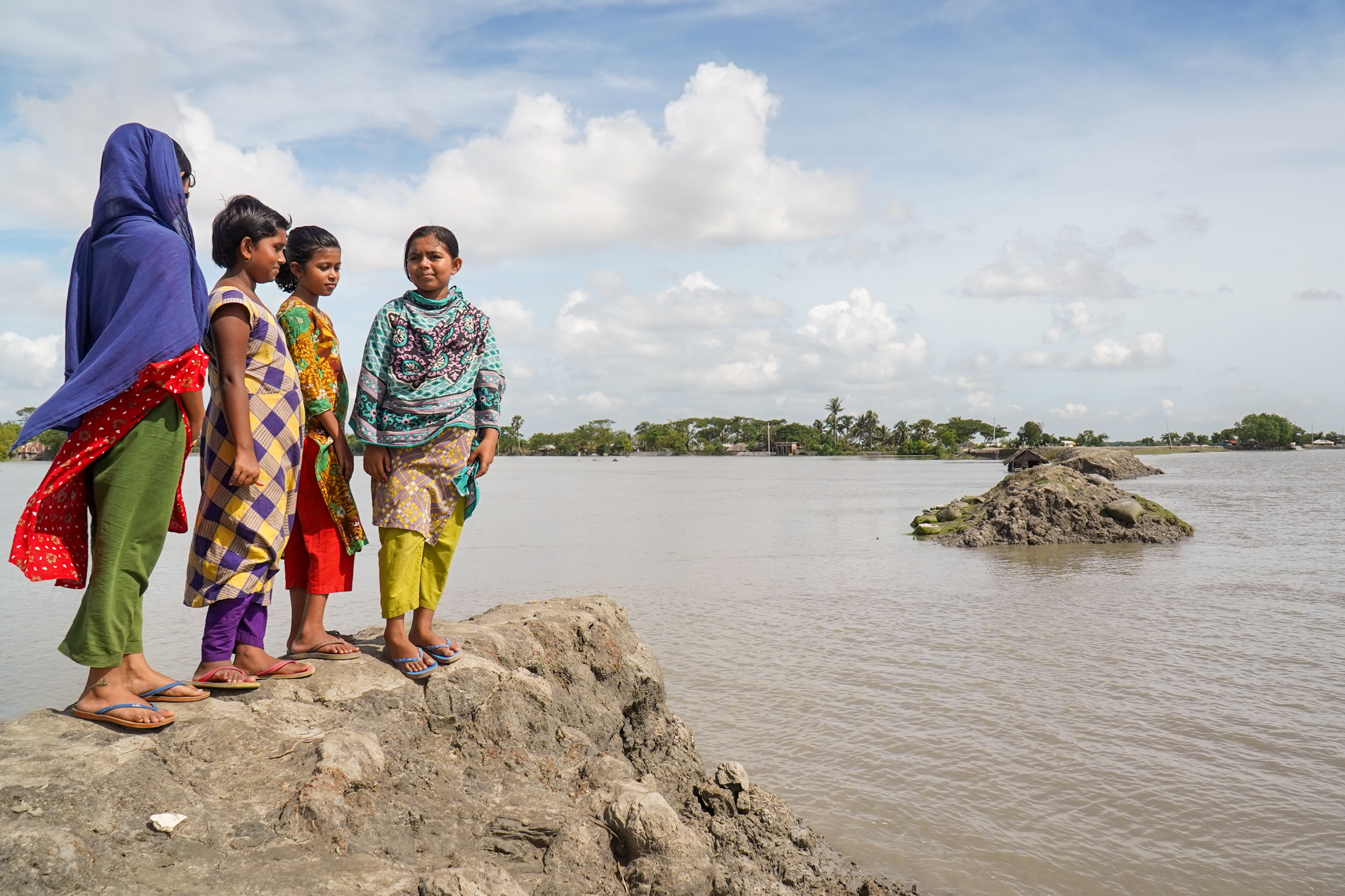Children on the shore near an embankment damaged by Cyclone Amphan, and not repaired due to COVID-19 disruptions.