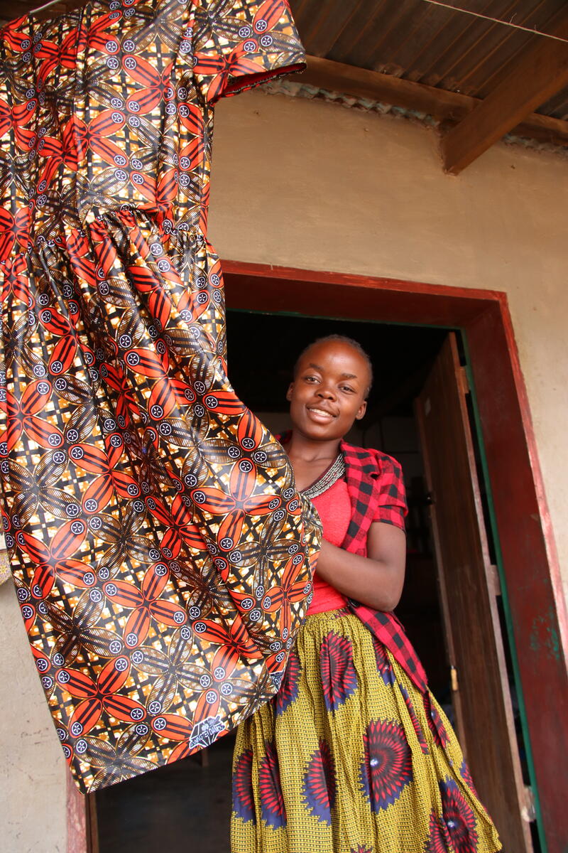 19-year-old sponsored child Mwila showing off a dress she stitched with African patterned fabric, thanks to the skill training she received.