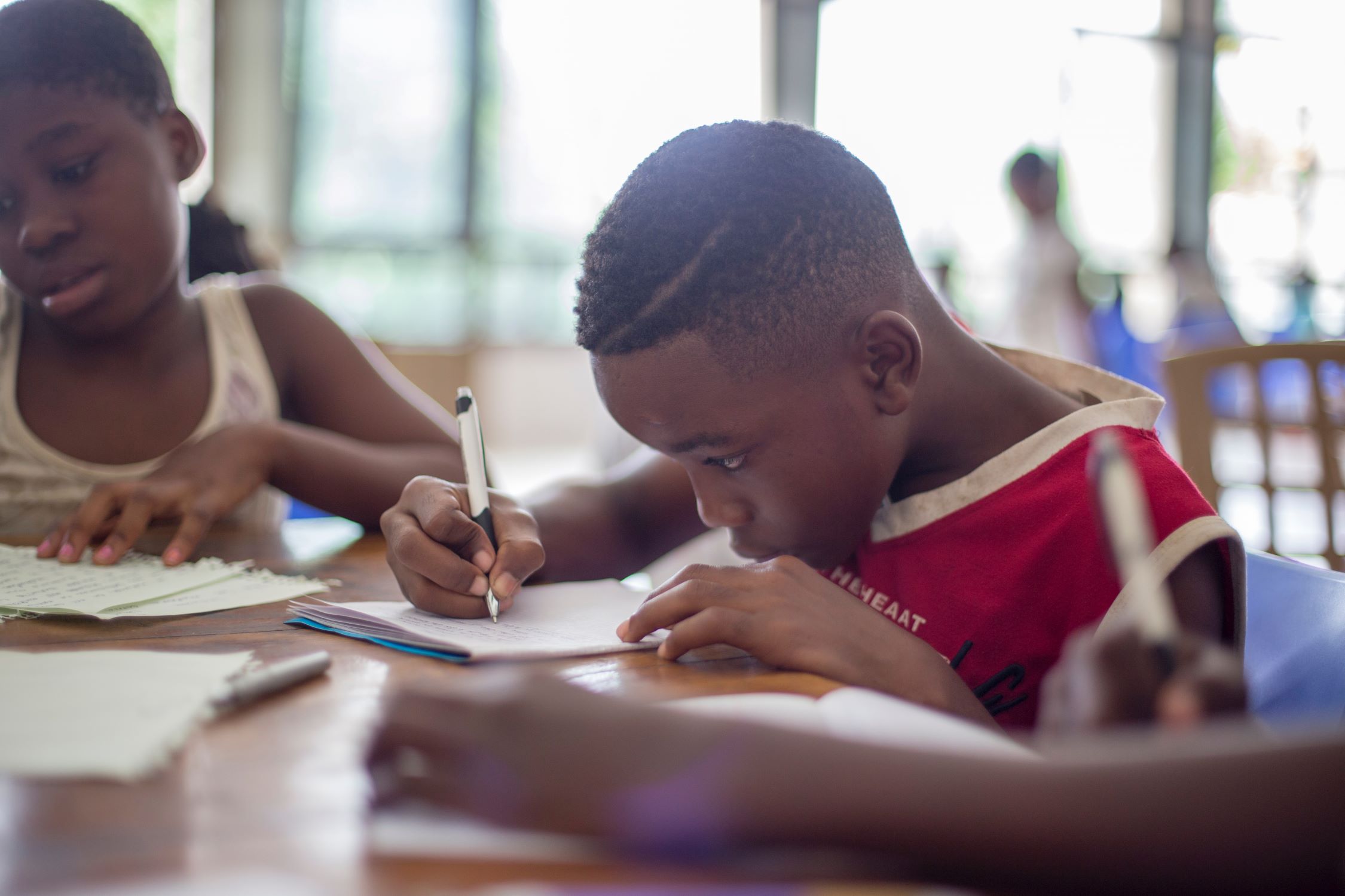 A child sits at a desk, writing