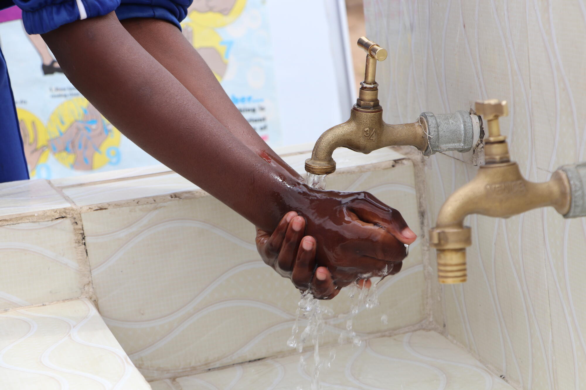 A pair of hands being washed under two taps