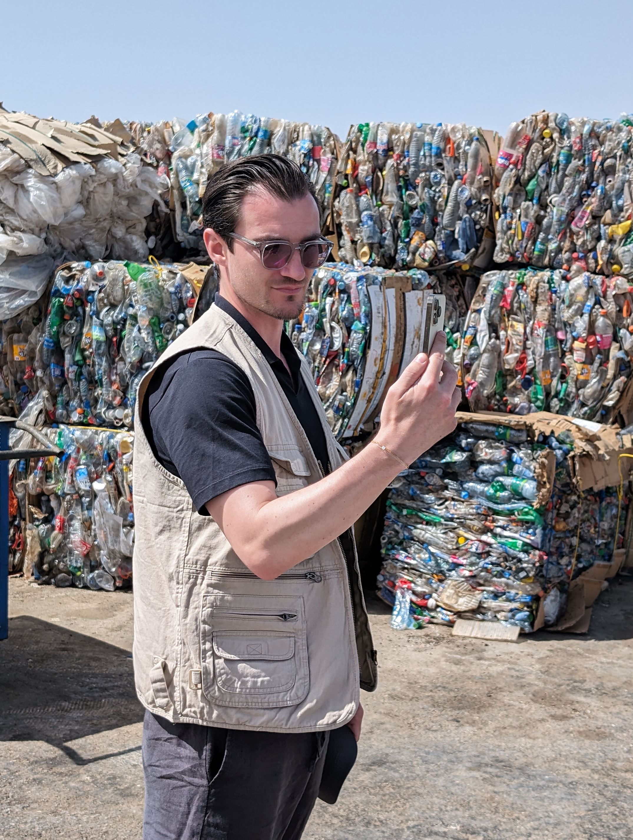 Brett records on his phone in front of high piles of clothing