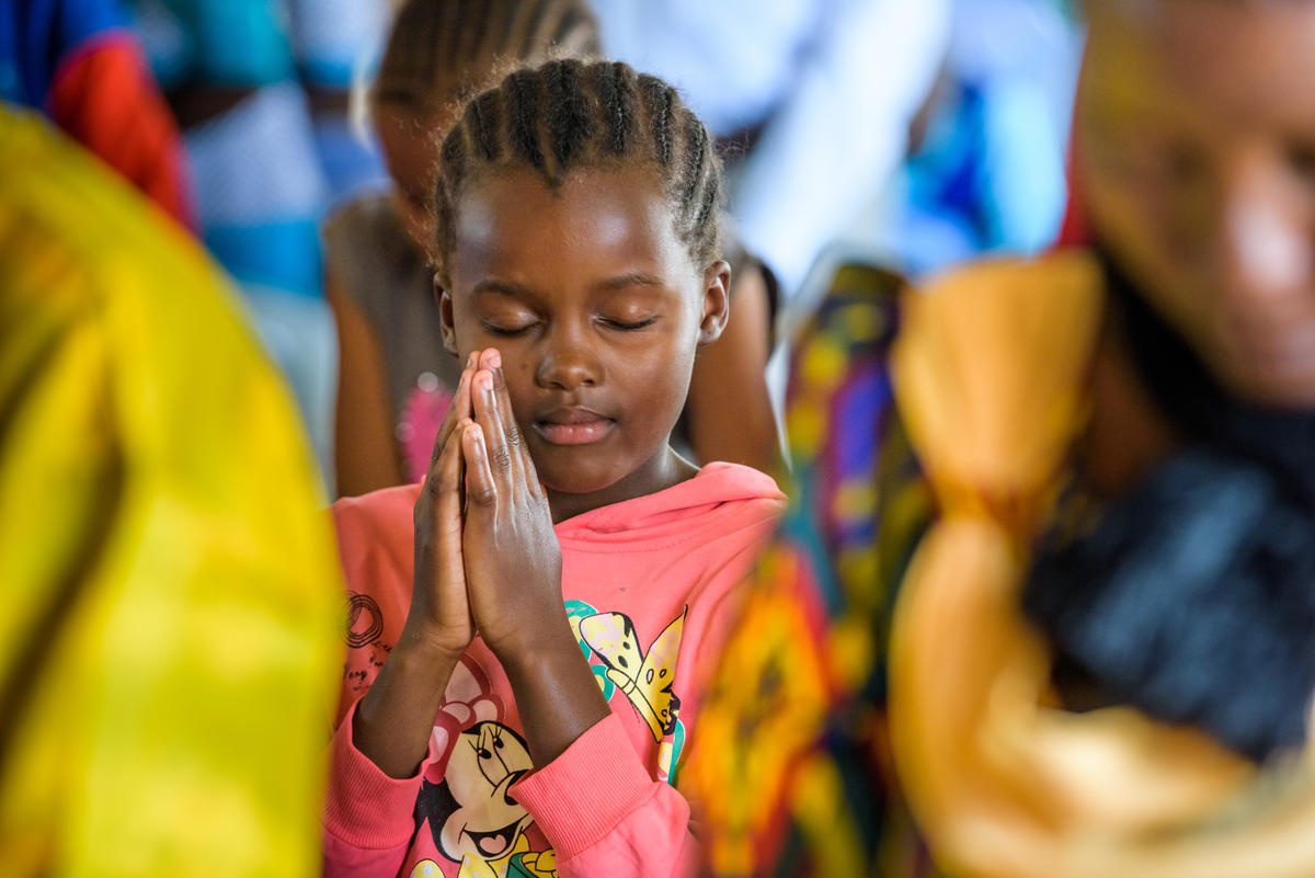 A child holding her hands together in prayer