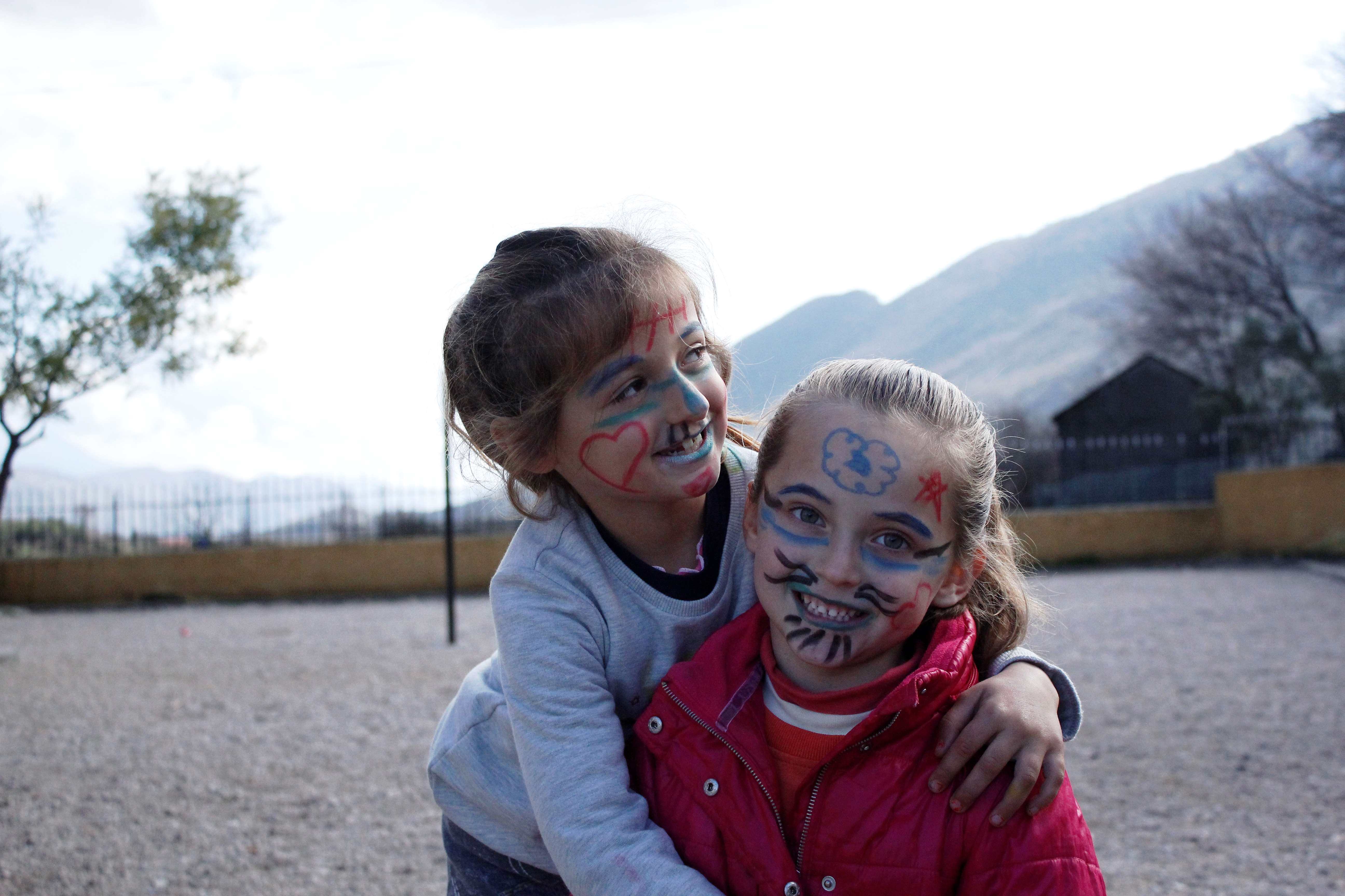 Two girls in Albania smile broadly as they hug and play outside on World Childrens Day