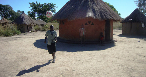 Child playing with a ball outside their home in Zambia
