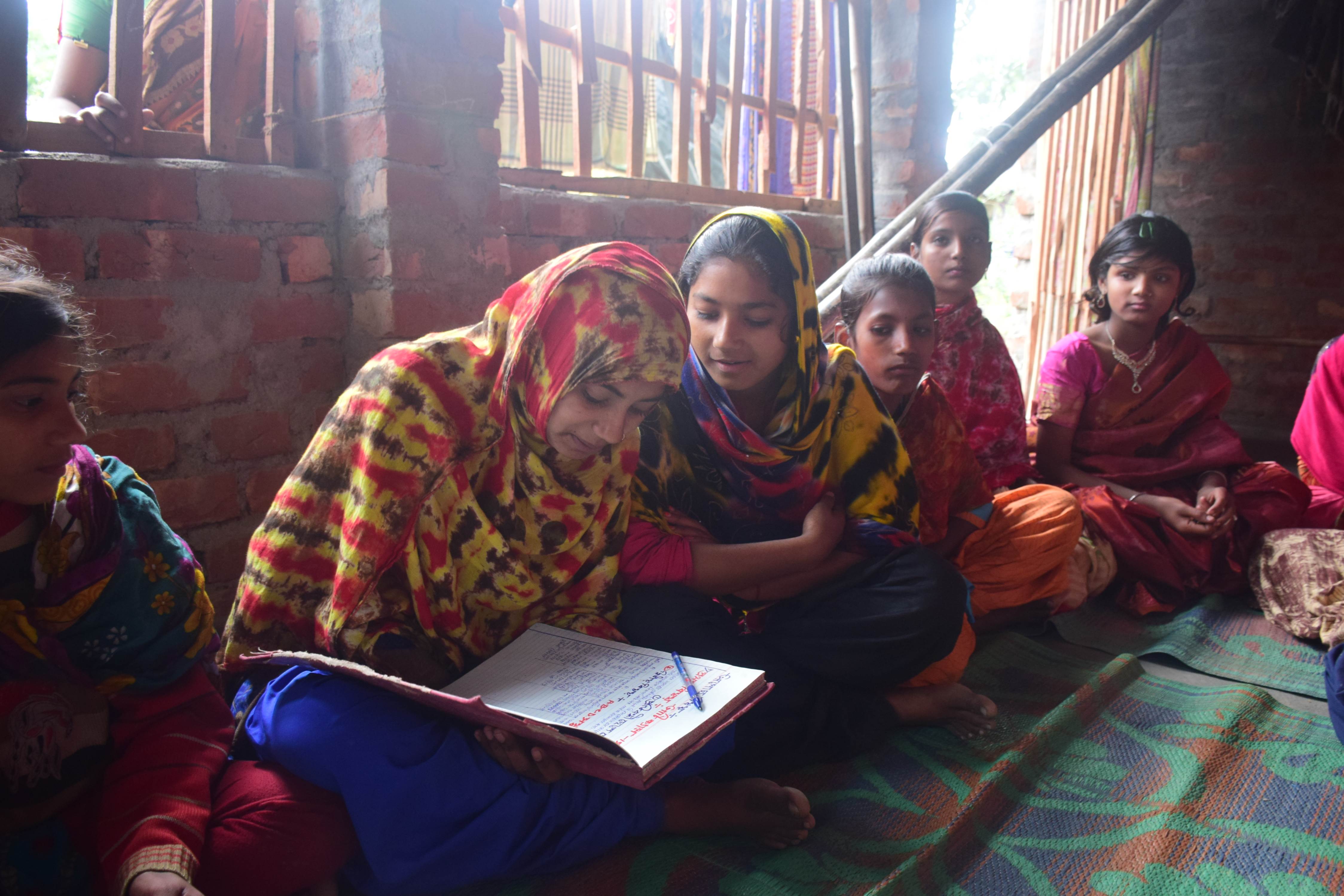 Girls in India sit on the floor of the classroom learning together