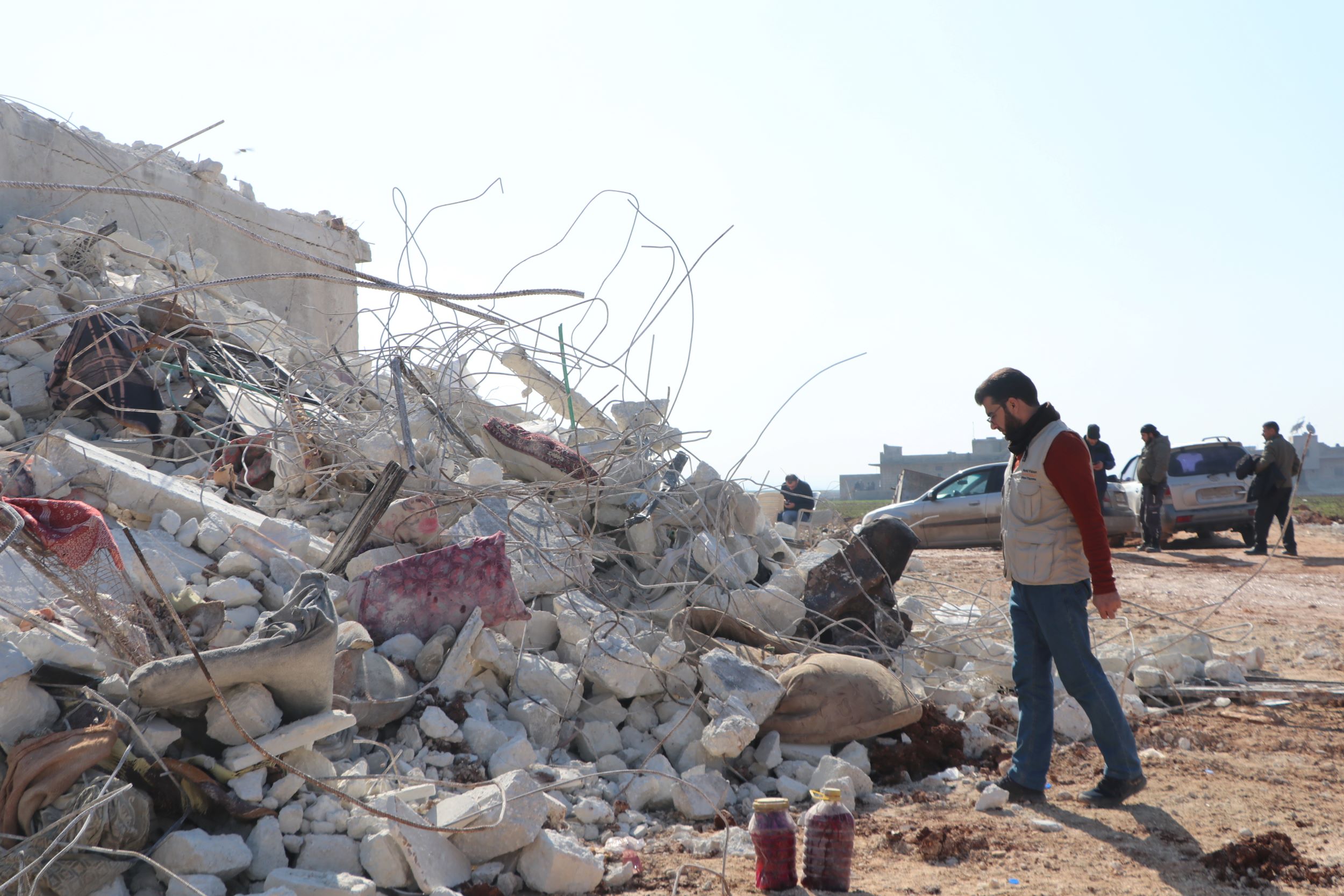 World Vision staff member standing before earthquake rubble, Syria
