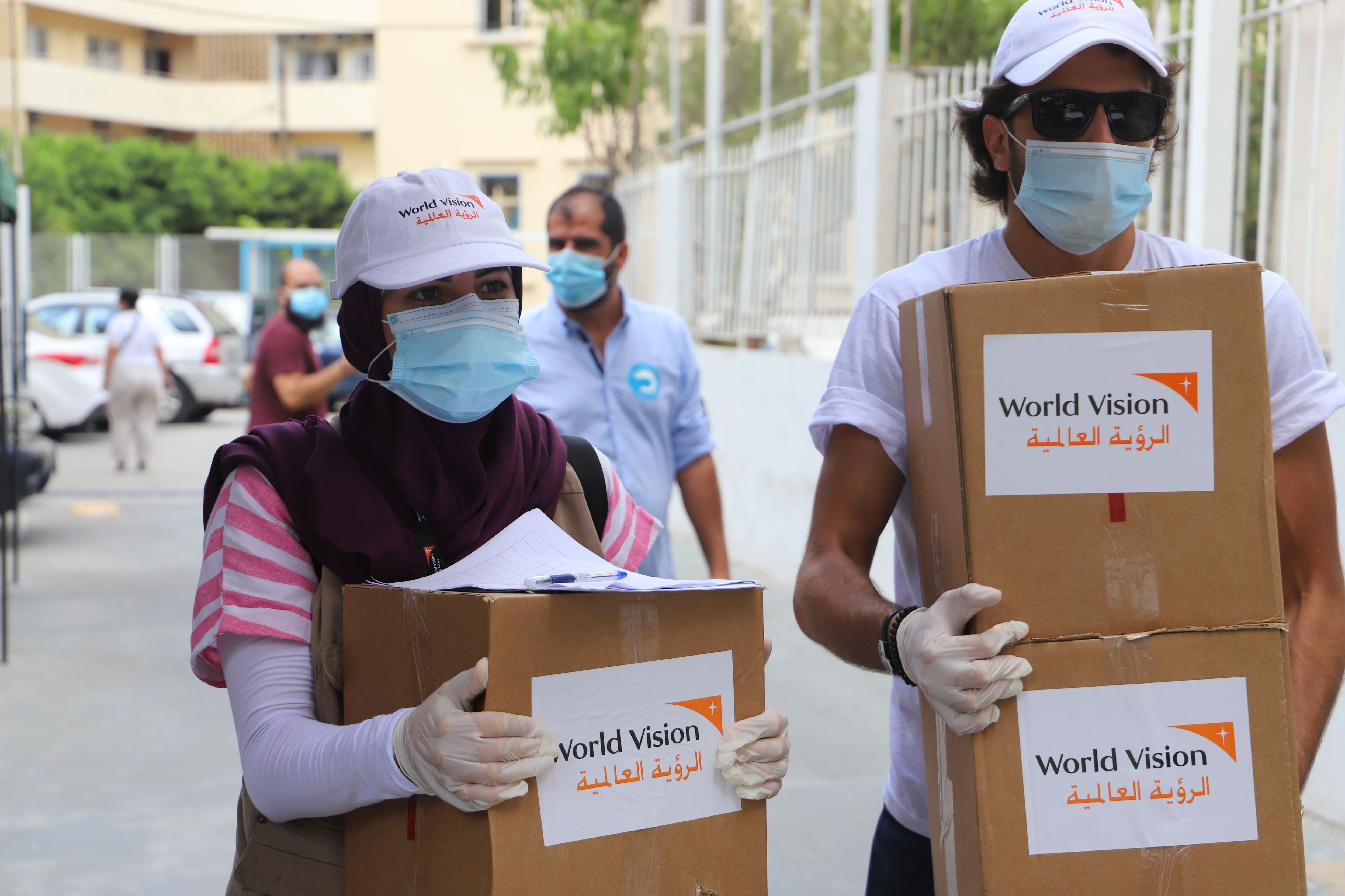 World Vision workers wearing masks hold boxes of food supplies to support people in Lebanon after the Beirut explosion