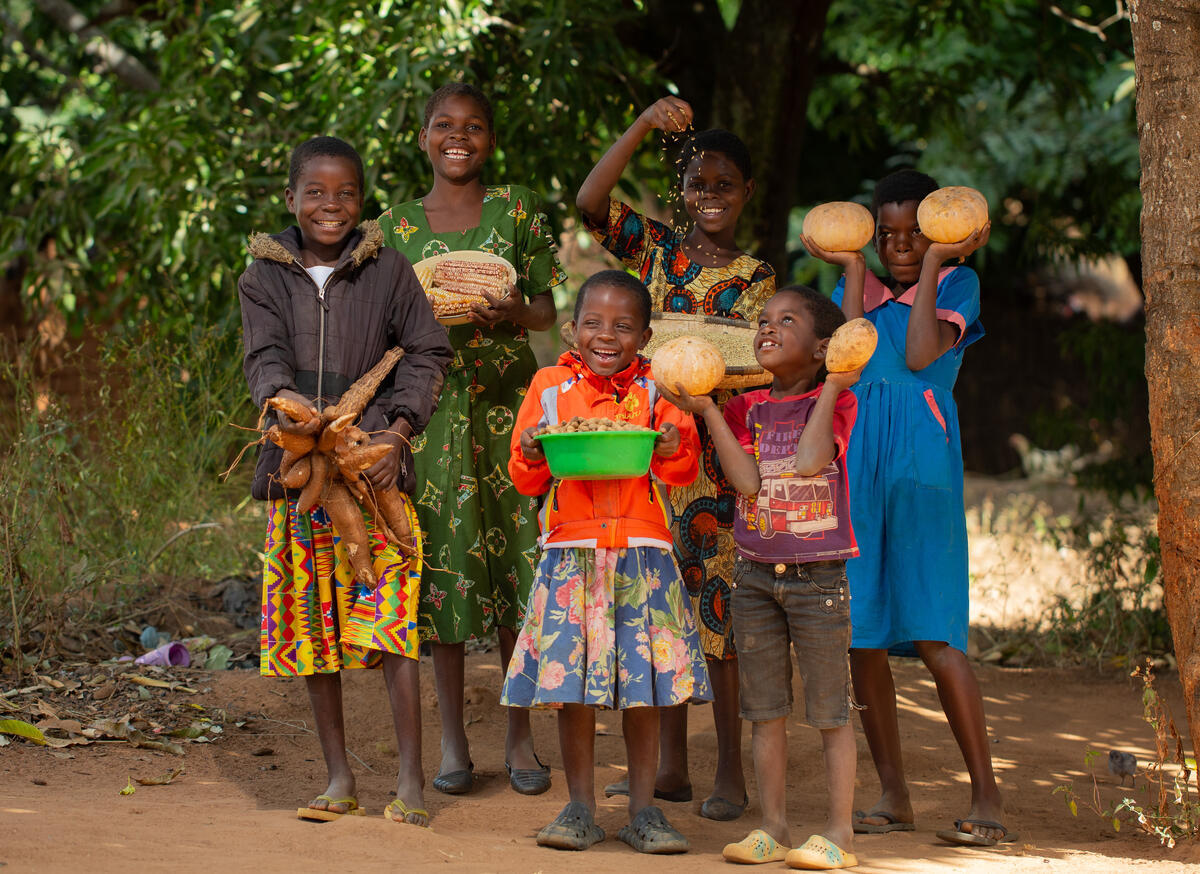 Six children from Malawi holding up the vegetables they harvested