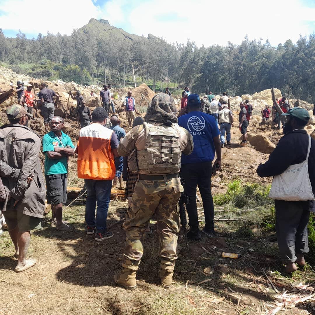 Rescue staff and volunteers stand amidst the landslide searching for survivors