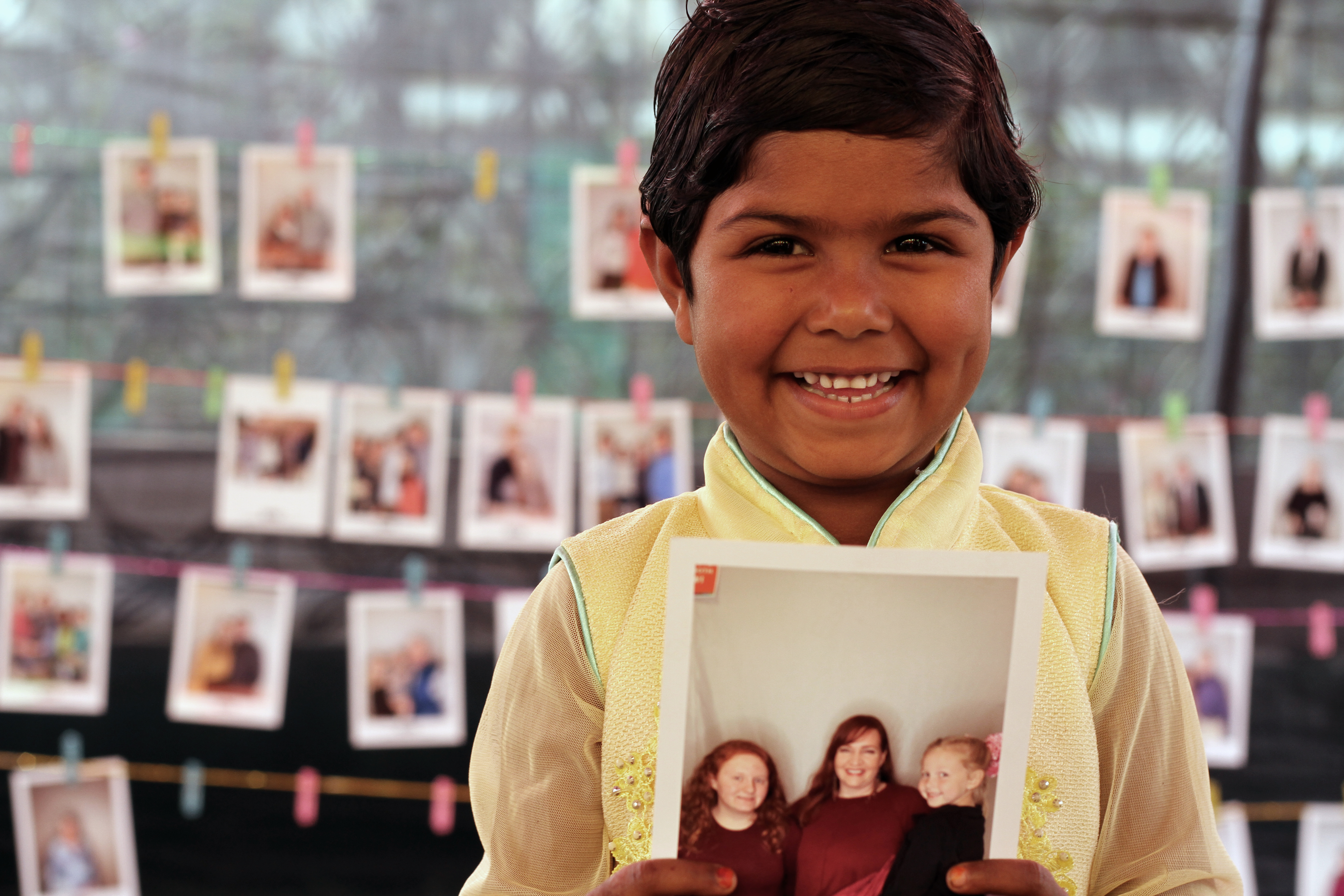 A young girl in Bangladesh beams and holds the photo of her new child sponsors