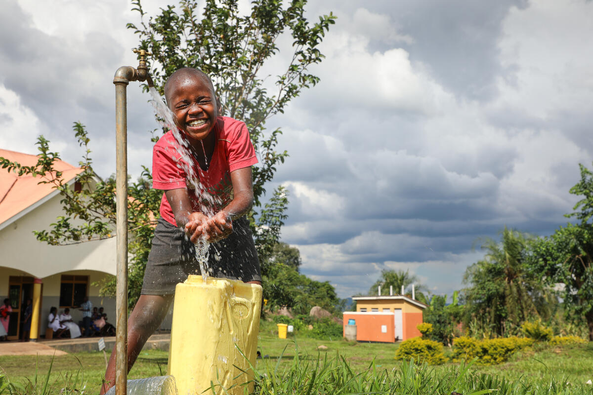 Ugandan girl holds hands underneath a hygiene station
