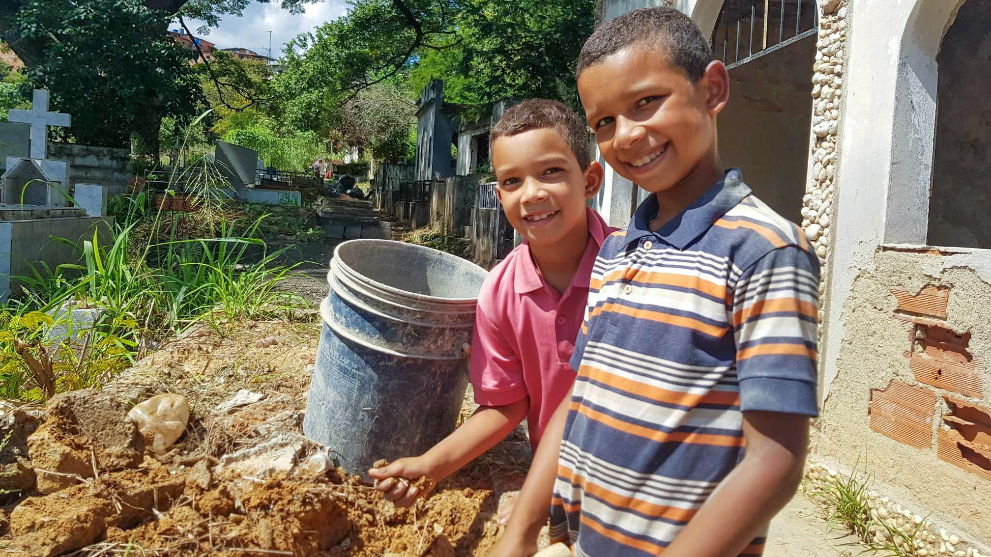 Two boys from Venezuela outside in their garden looking and smiling to the camera 