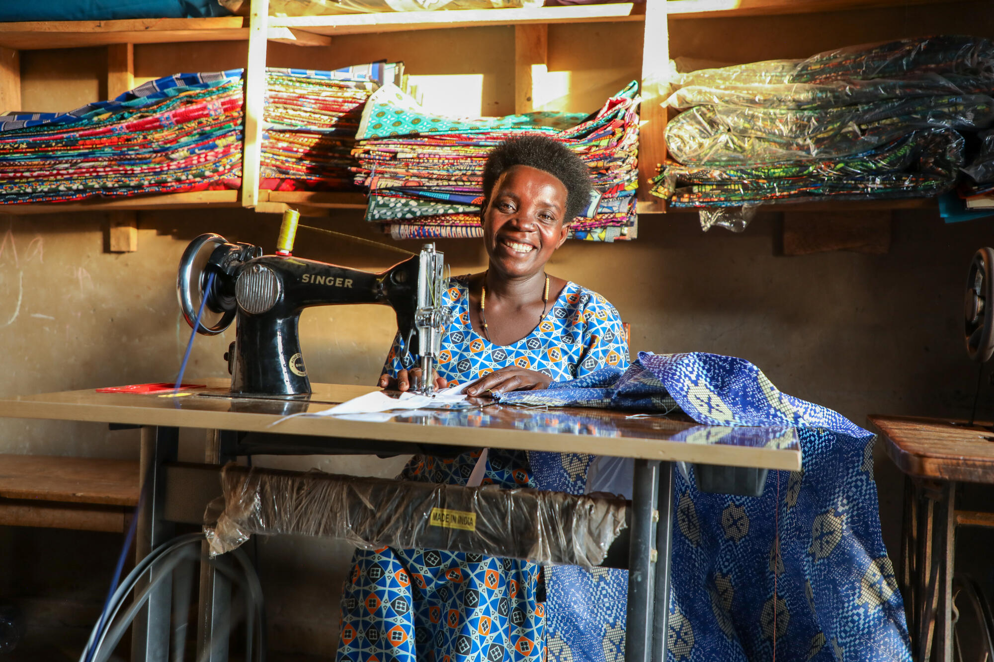 A lady sits at a sewing machine in Uganda