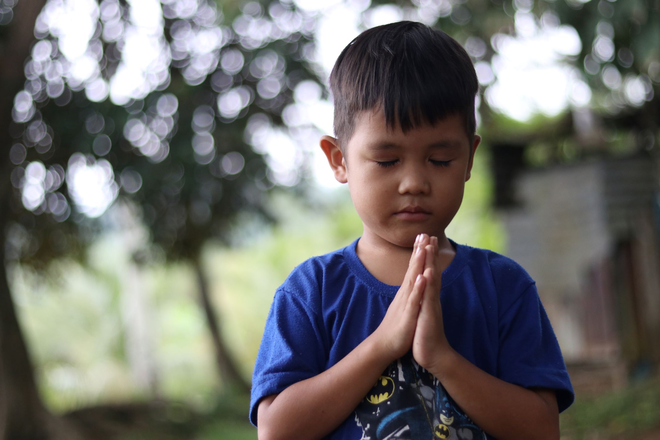 A child in the Philippines holding his hands together in prayer