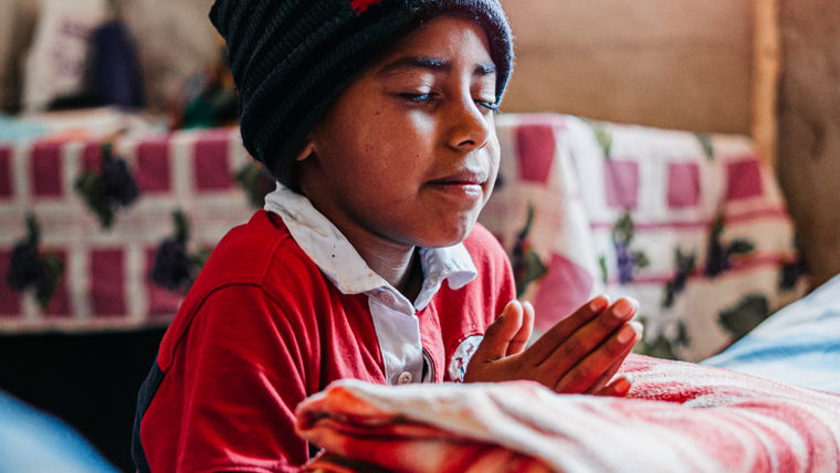 Victor kneels by his bed and prays.