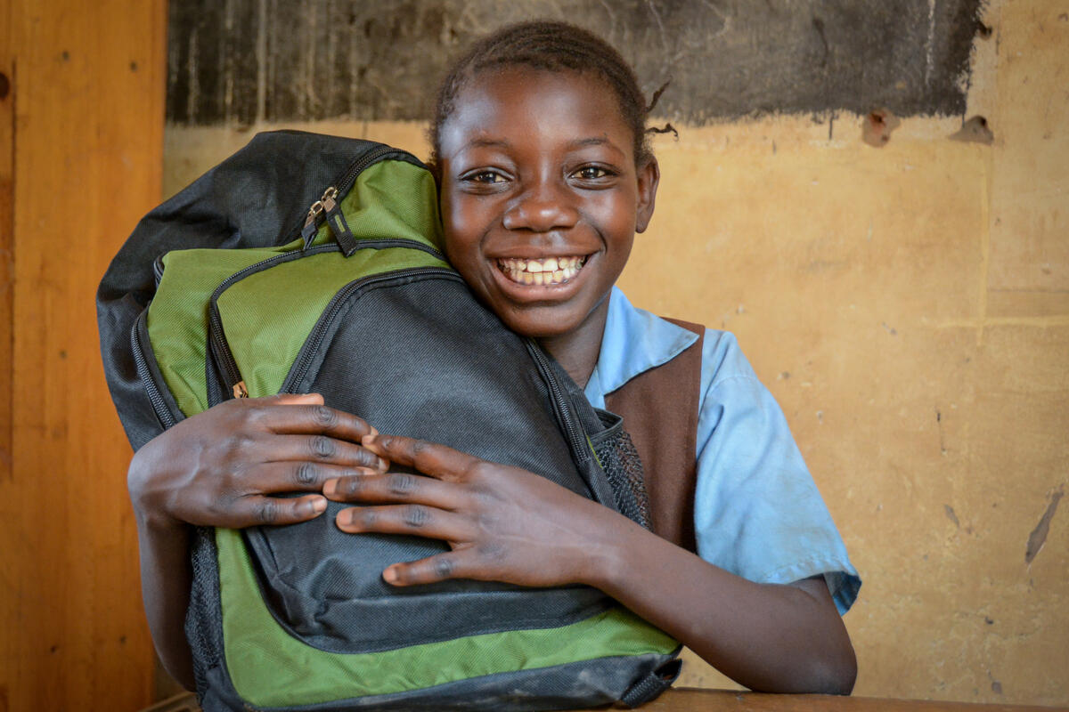 Schoolgirl in Zambia clutches backpack and smiles