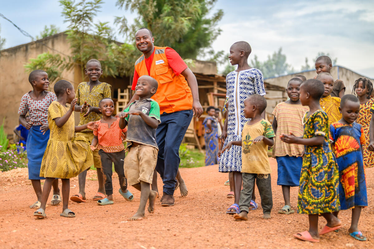 A staff member in Rwanda walks among a group of children