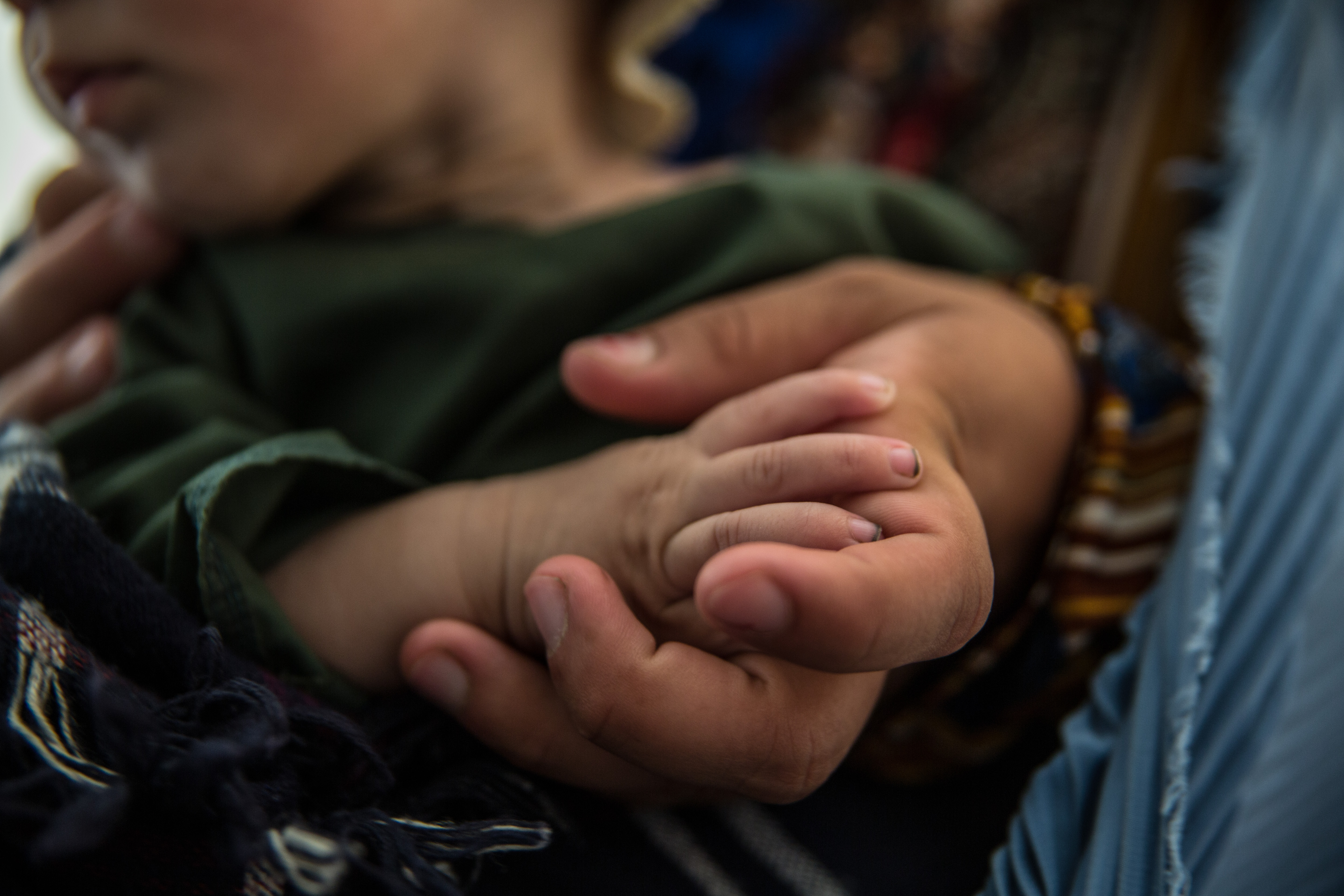 A close up of an adult hand holding a young child's hand.