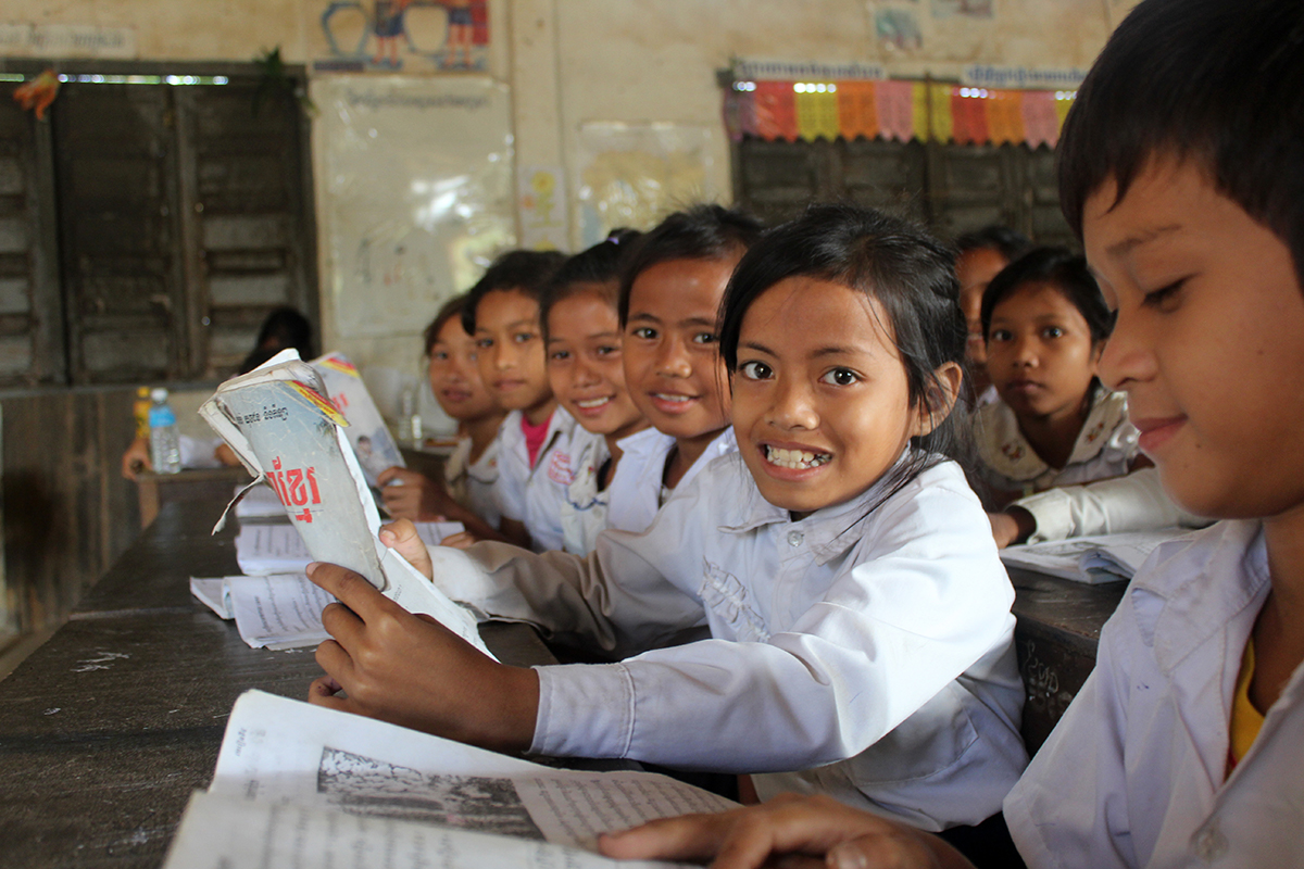 Children sitting in a classroom smile at the camera