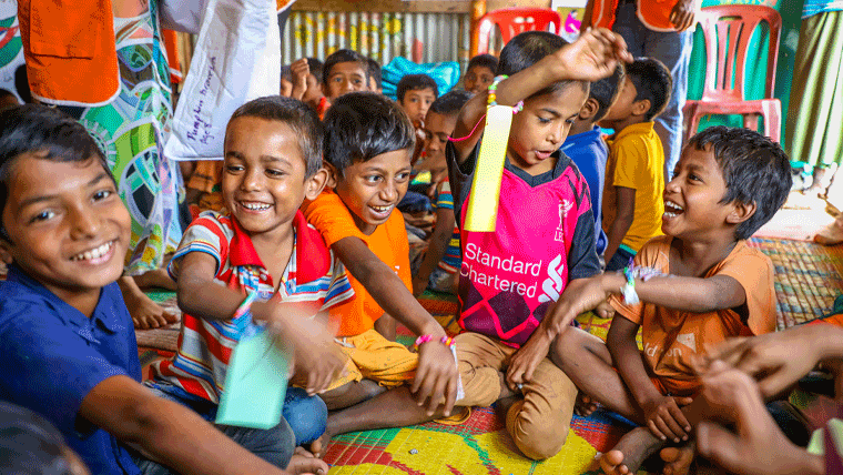 Rohingya refugee children in Bangladesh excitedly show each other the buddy bracelets made for them by children in the UK
