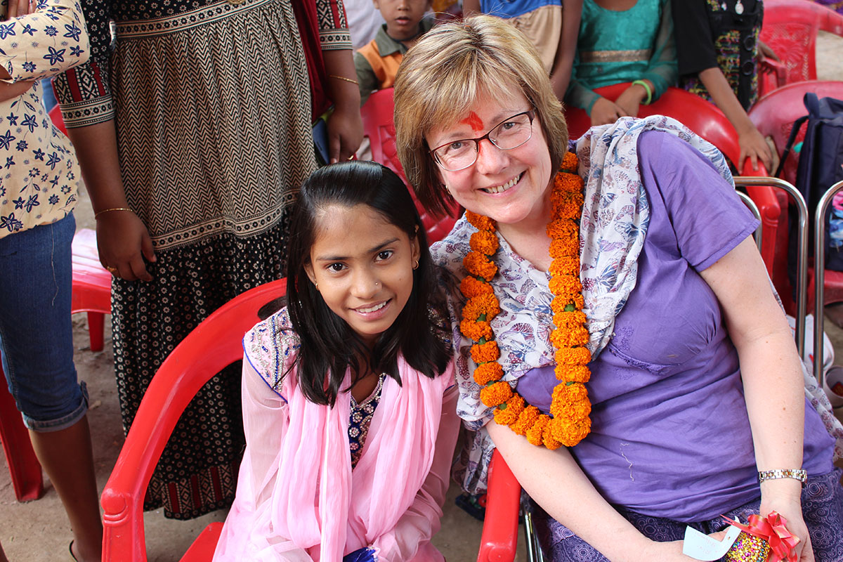 Woman and girl sit on plastic chairs together in India
