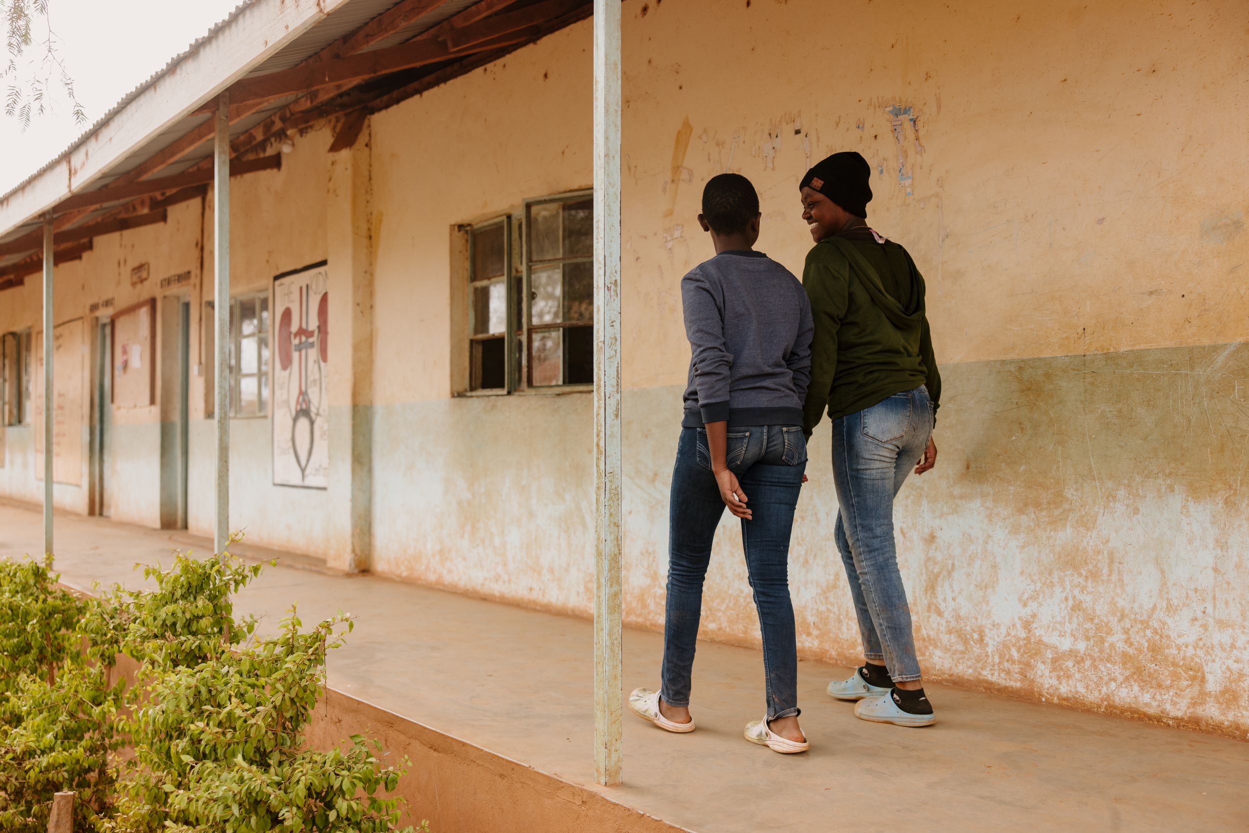 Two girls walking outside a building with faded walls