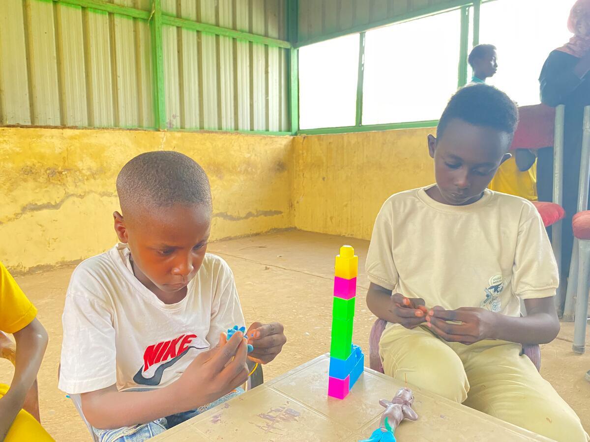 two Sudanese boys playing with plastic building blocks