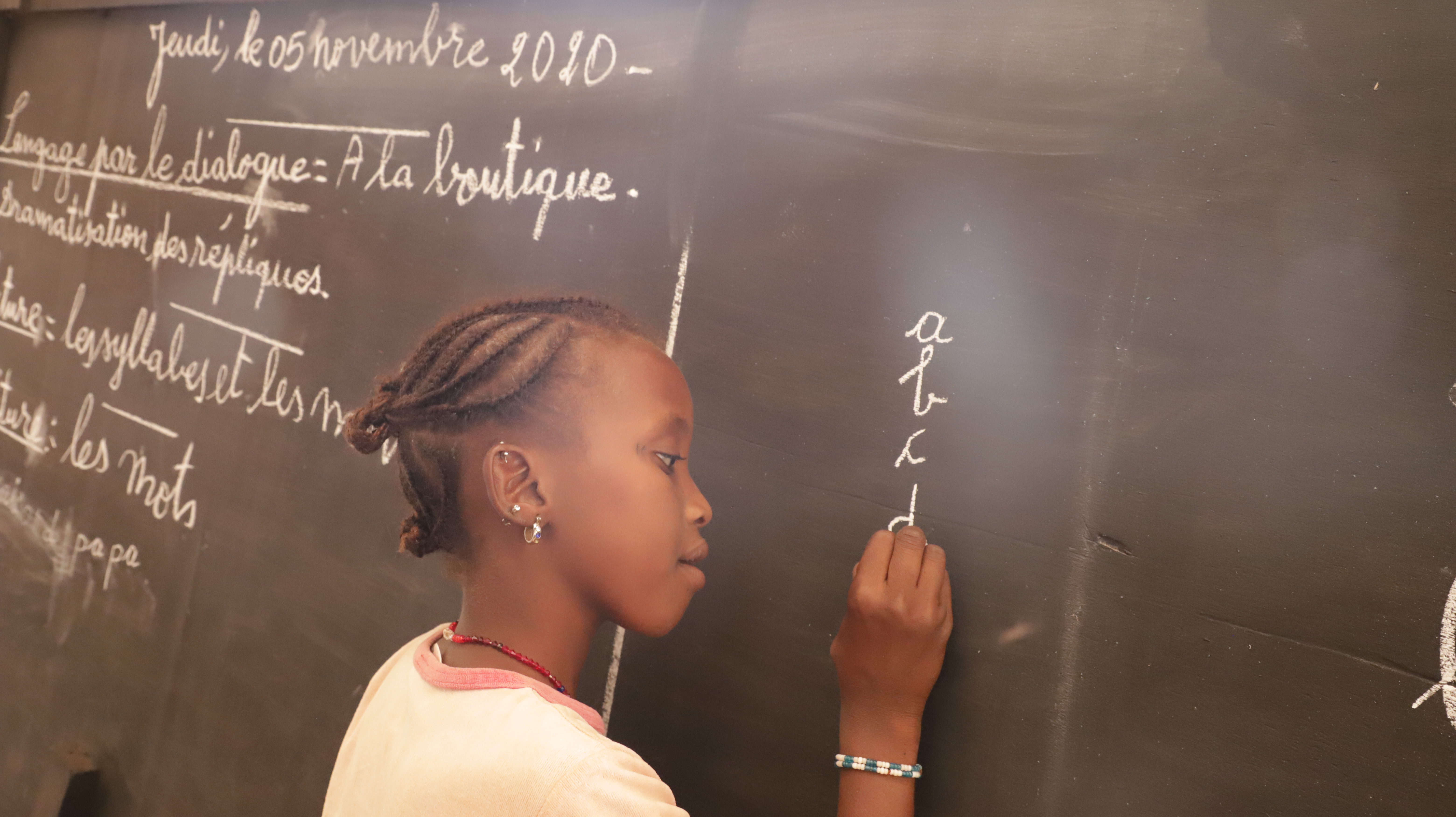 Girl in Mali writes on a blackboard - attempting to continue her schooling despite the impact of COVID-19